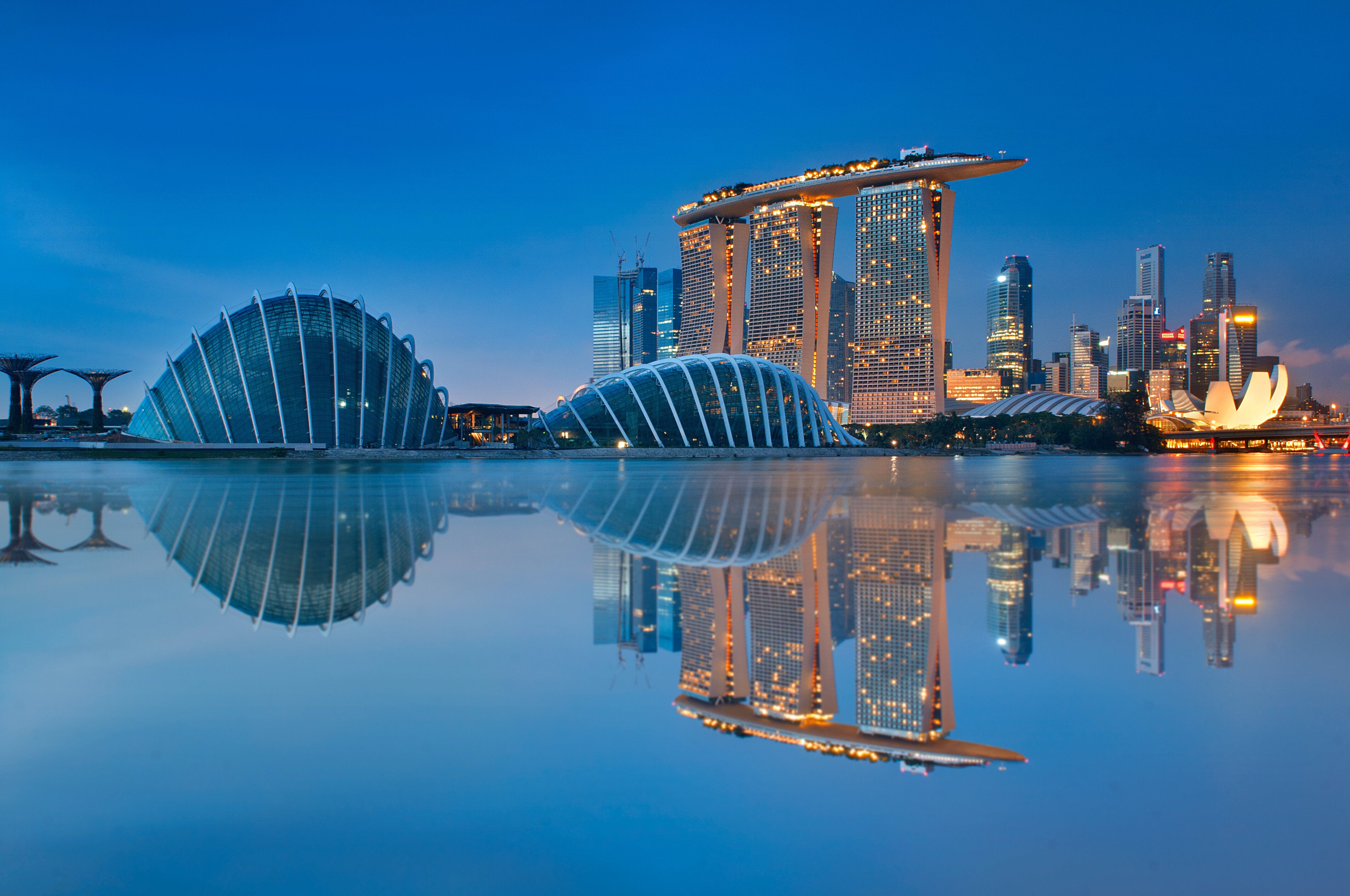 Skyline of Singapore with the Marina Bay Sands, futuristic buildings, and their reflections in the water during twilight