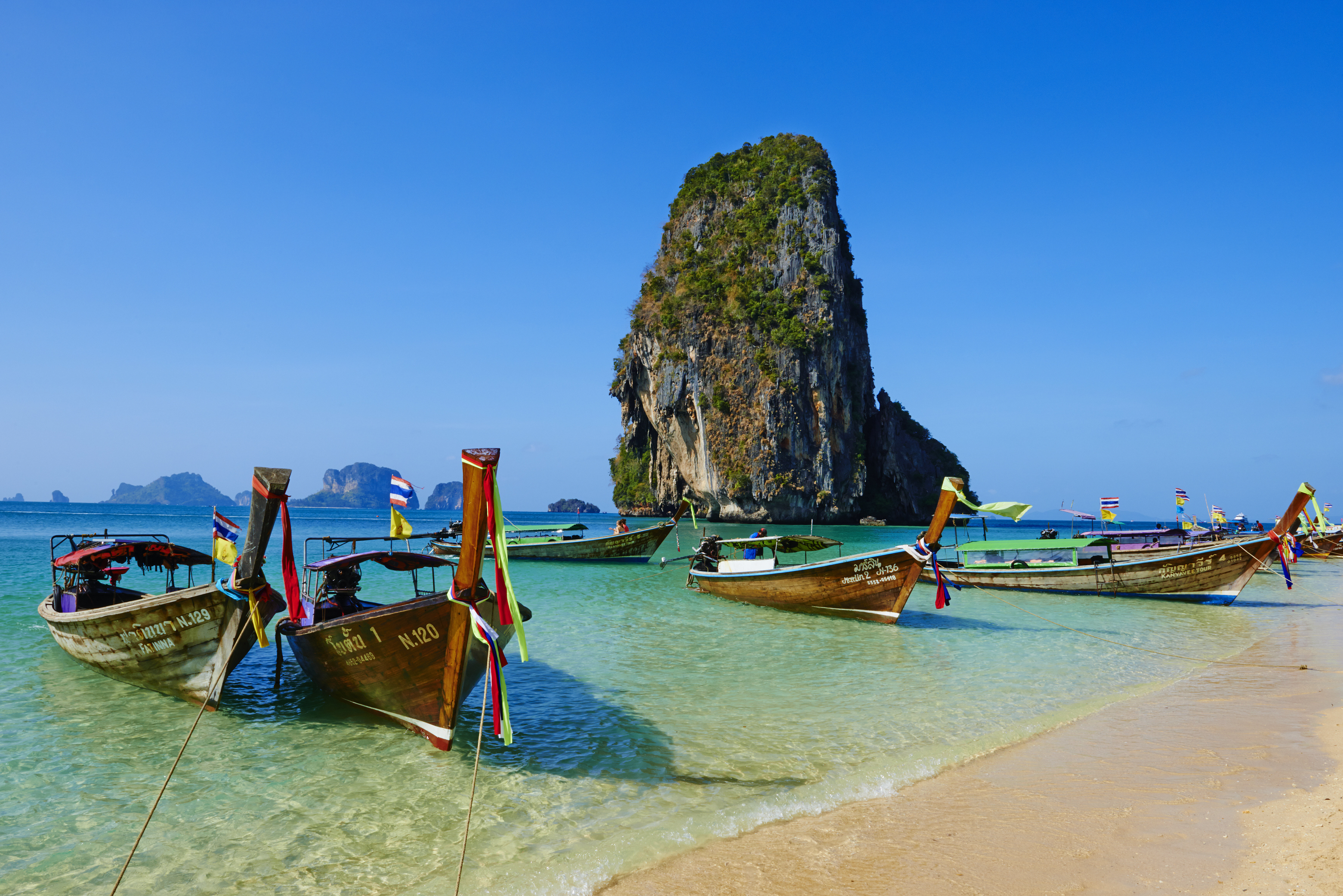 Turquoise blue water with ships lining the shore line in Thailand