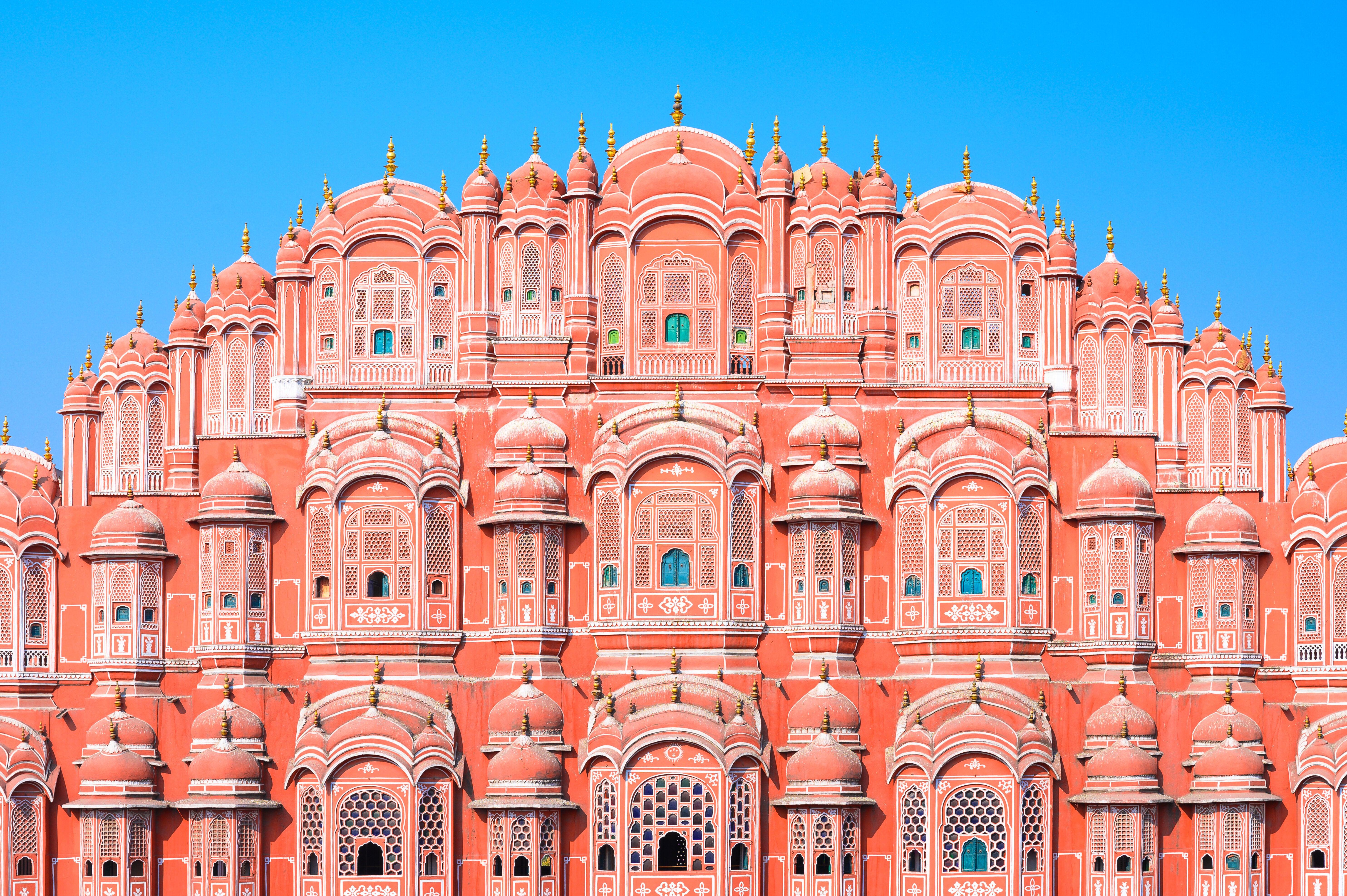 Hawa Mahal, a historic palace in Jaipur, India, features intricate architecture with numerous small windows and domes against a clear sky
