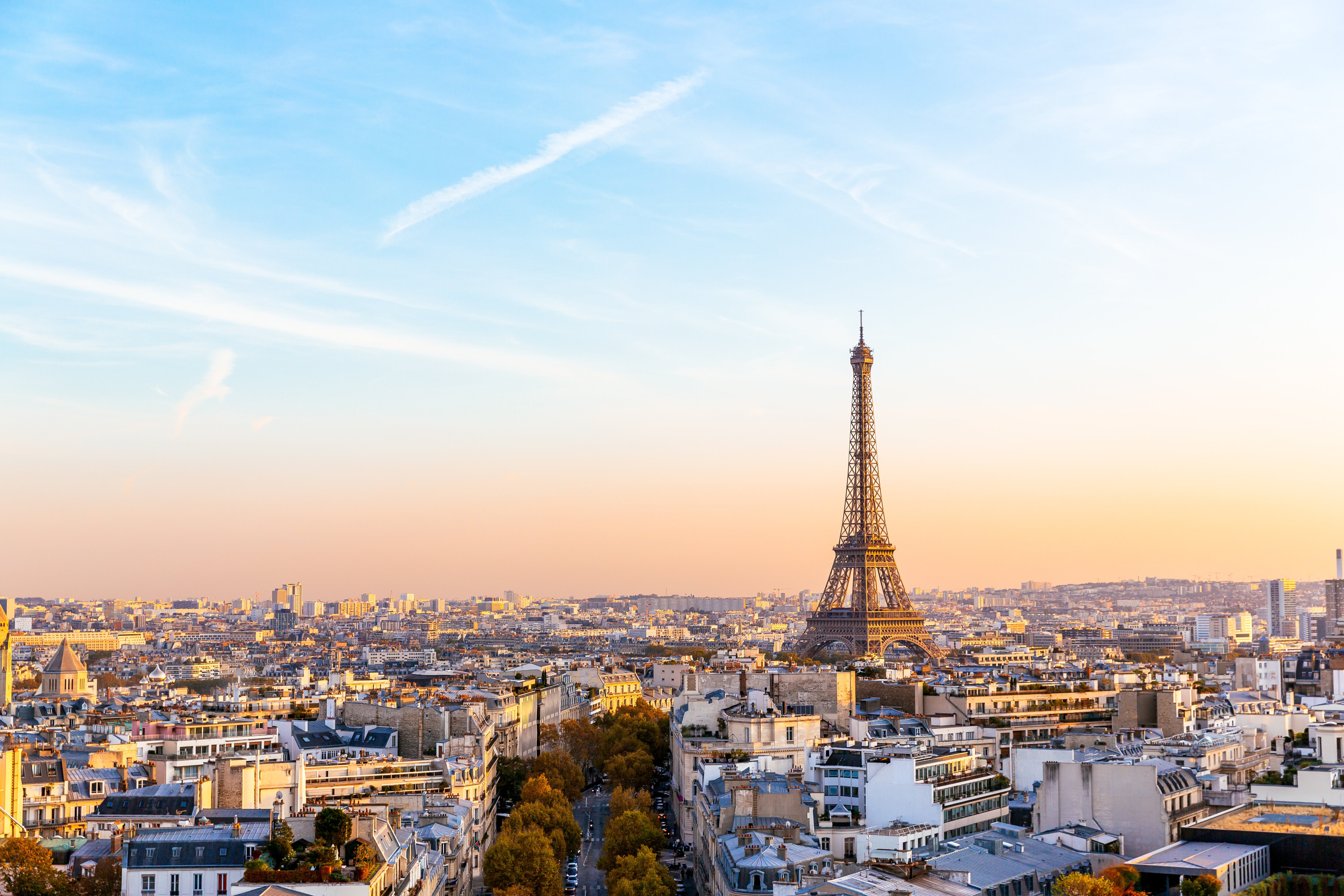Aerial view of Paris with the Eiffel Tower centered, surrounded by city buildings under a clear sky