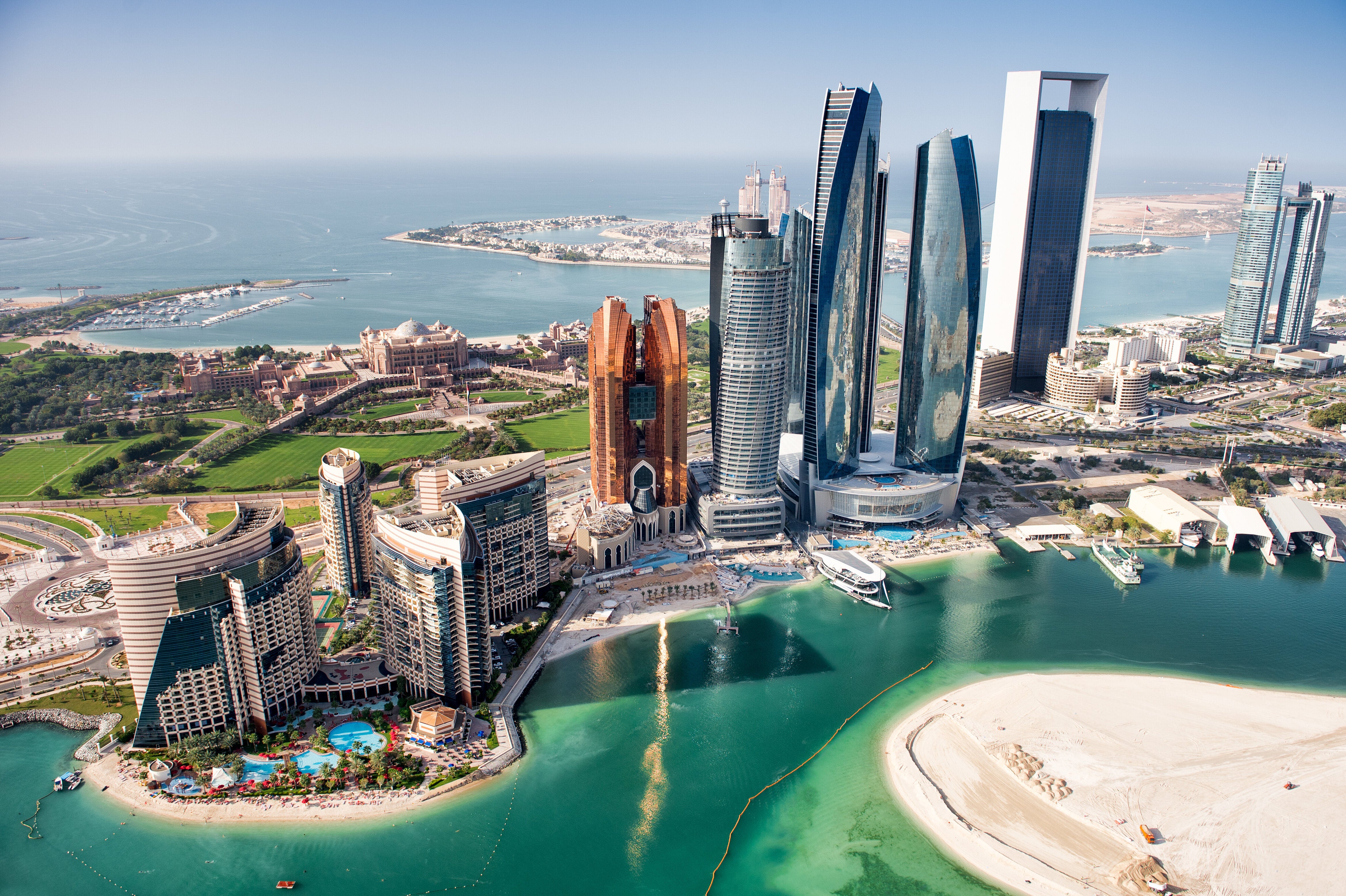 Aerial view of Abu Dhabi's skyline featuring modern skyscrapers, waterfront, and surrounding islands