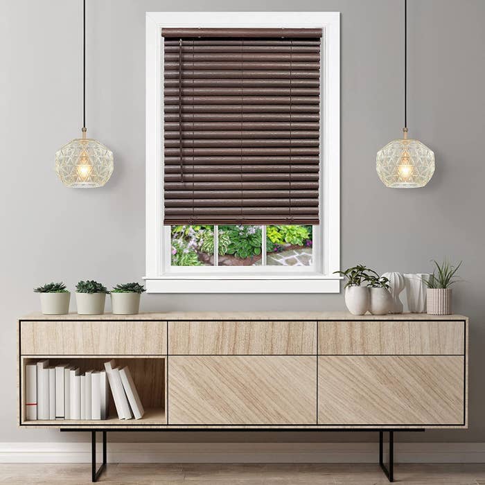 Modern surviving  country   with a neutral-tone sideboard, potted plants, books, 2  pendant lights, and a model   featuring brownish  blinds