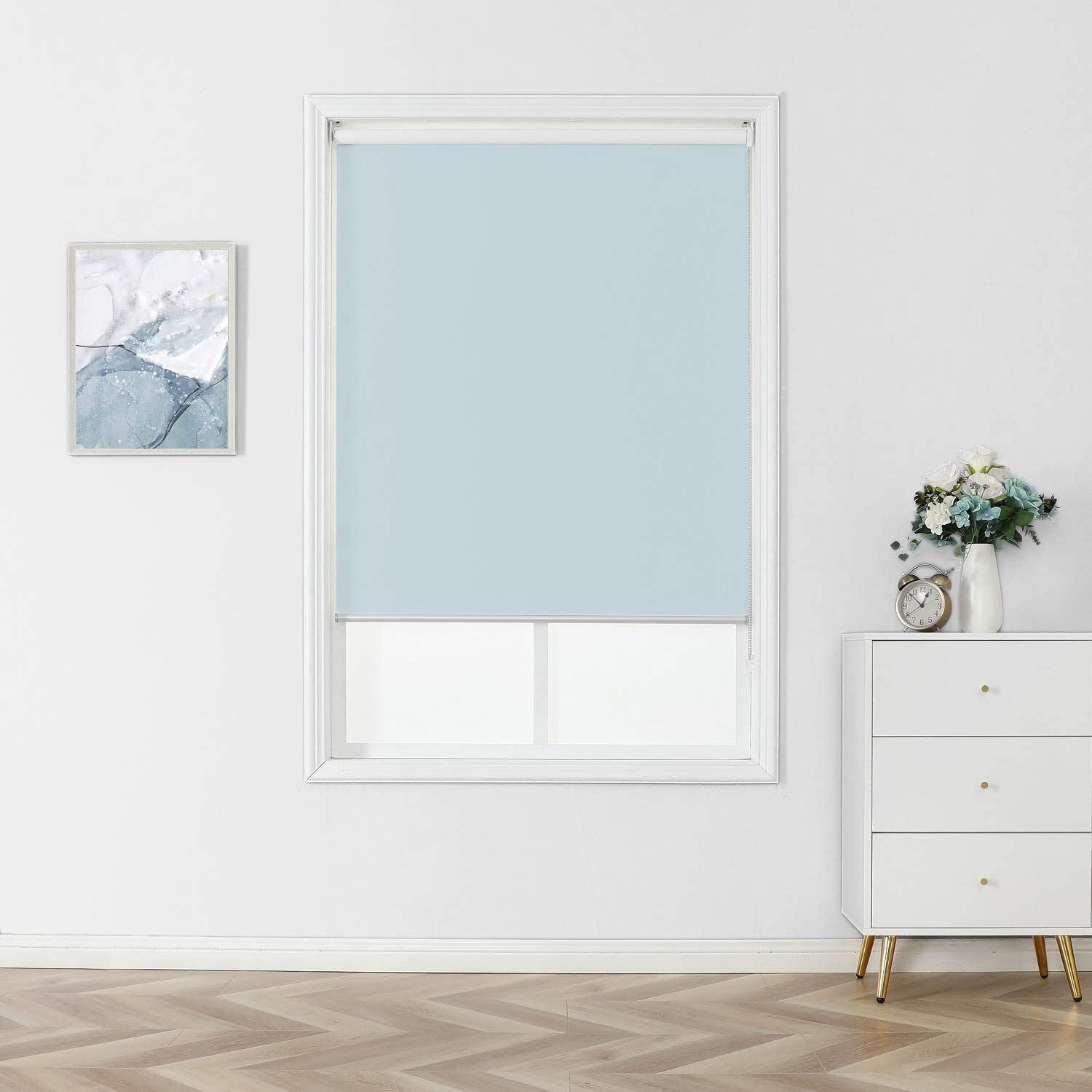 Room with a bluish  roller unsighted  connected  a window, achromatic  thorax  with a timepiece  and flowers, and a framed abstract representation   connected  the wall