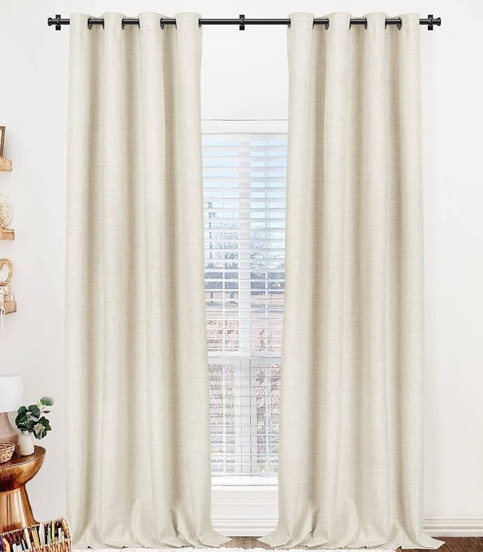 Neutral-hue curtains hanging connected  a rod, partially covering a model   with blinds, successful  a well-decorated room