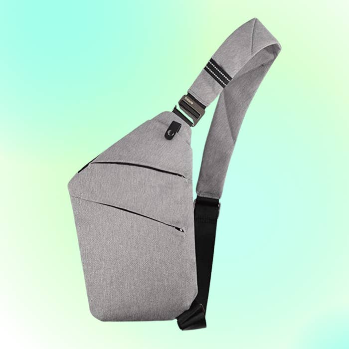 A modern, minimalist grey  sling container  with sleek, diagonal zippers and an adjustable strap, showcased against a gradient background