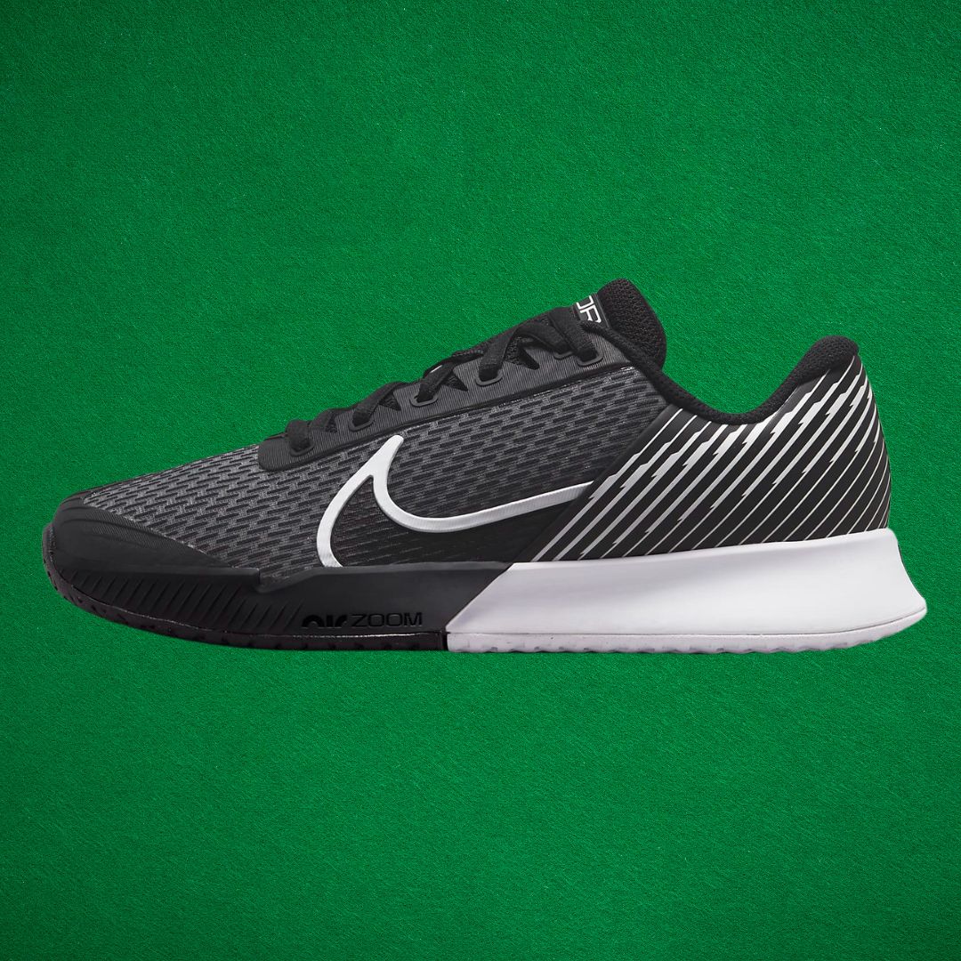A black and white sneaker with a Nike swoop against a dark green backgroumd