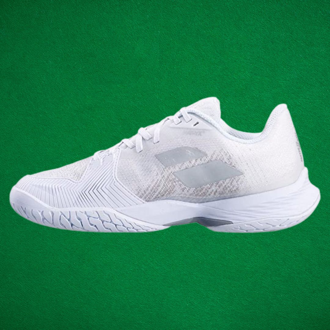 An all-white sneaker against a dark green background