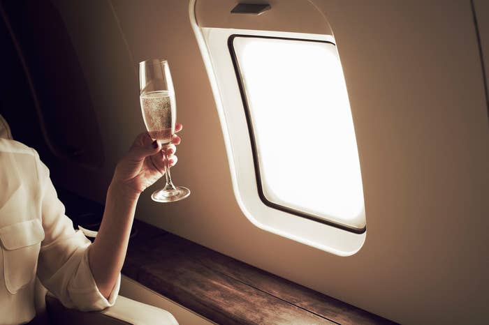 A person holding a glass of champagne on a plane