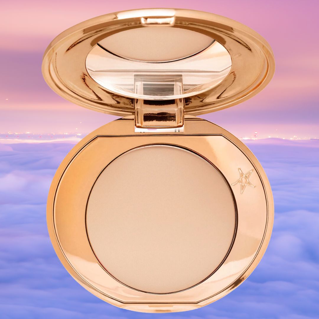 A compact makeup powder with a mirror, open and displayed against a cloudy sky background