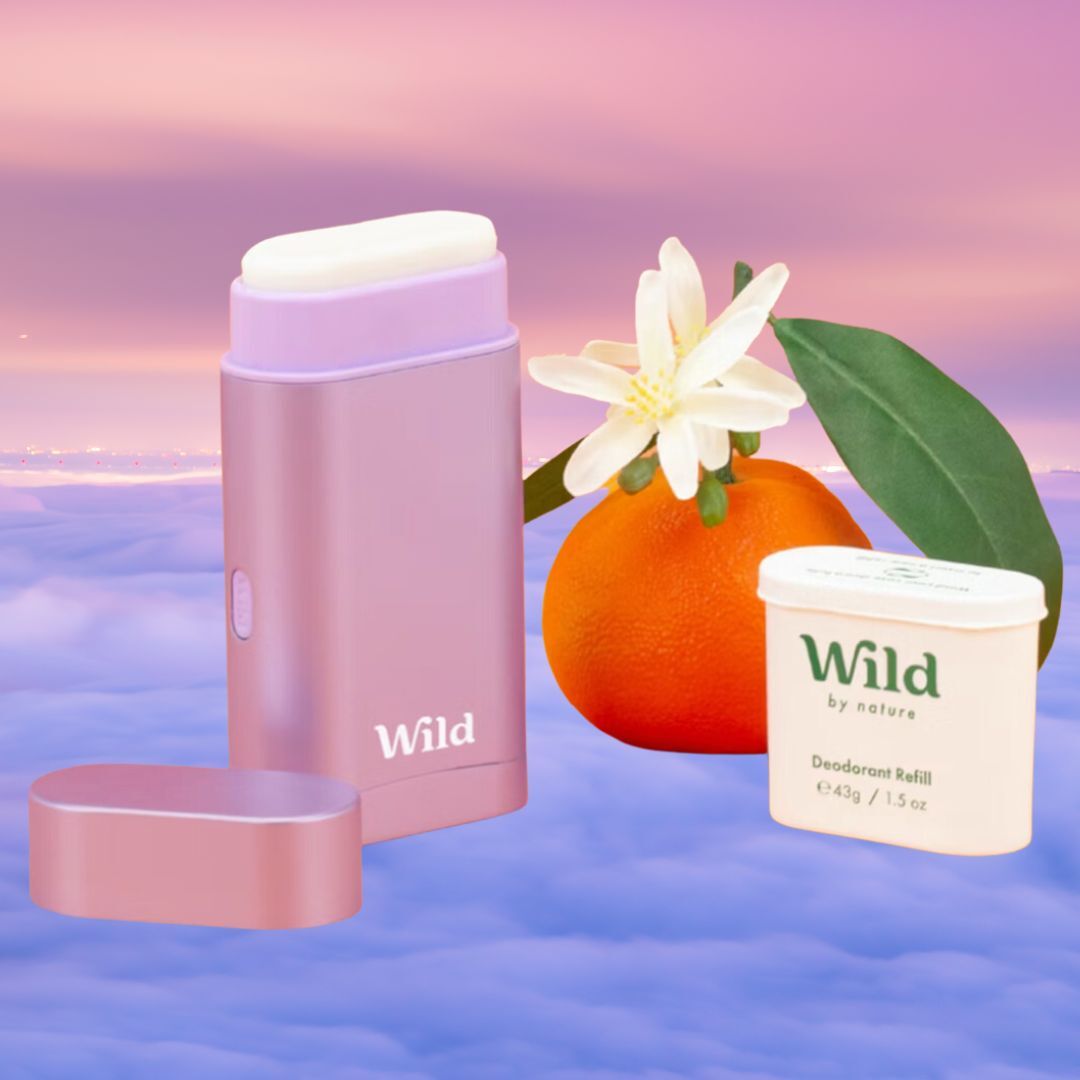 Wild by Nature deodorant stick and refill are displayed alongside a small orange and white flower, set against a cloud background