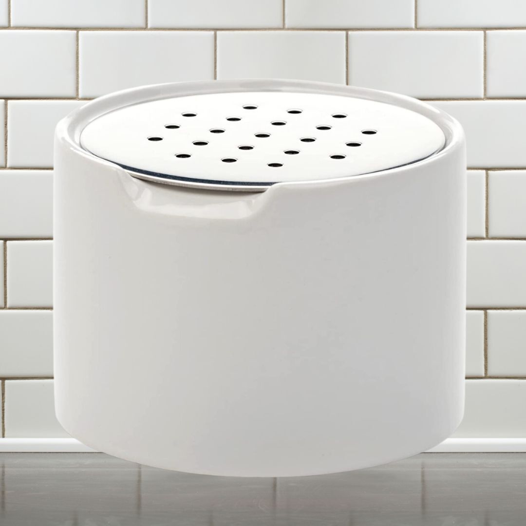 White ceramic compost keeper with a ventilated lid, placed connected  a room  antagonistic  with tile background