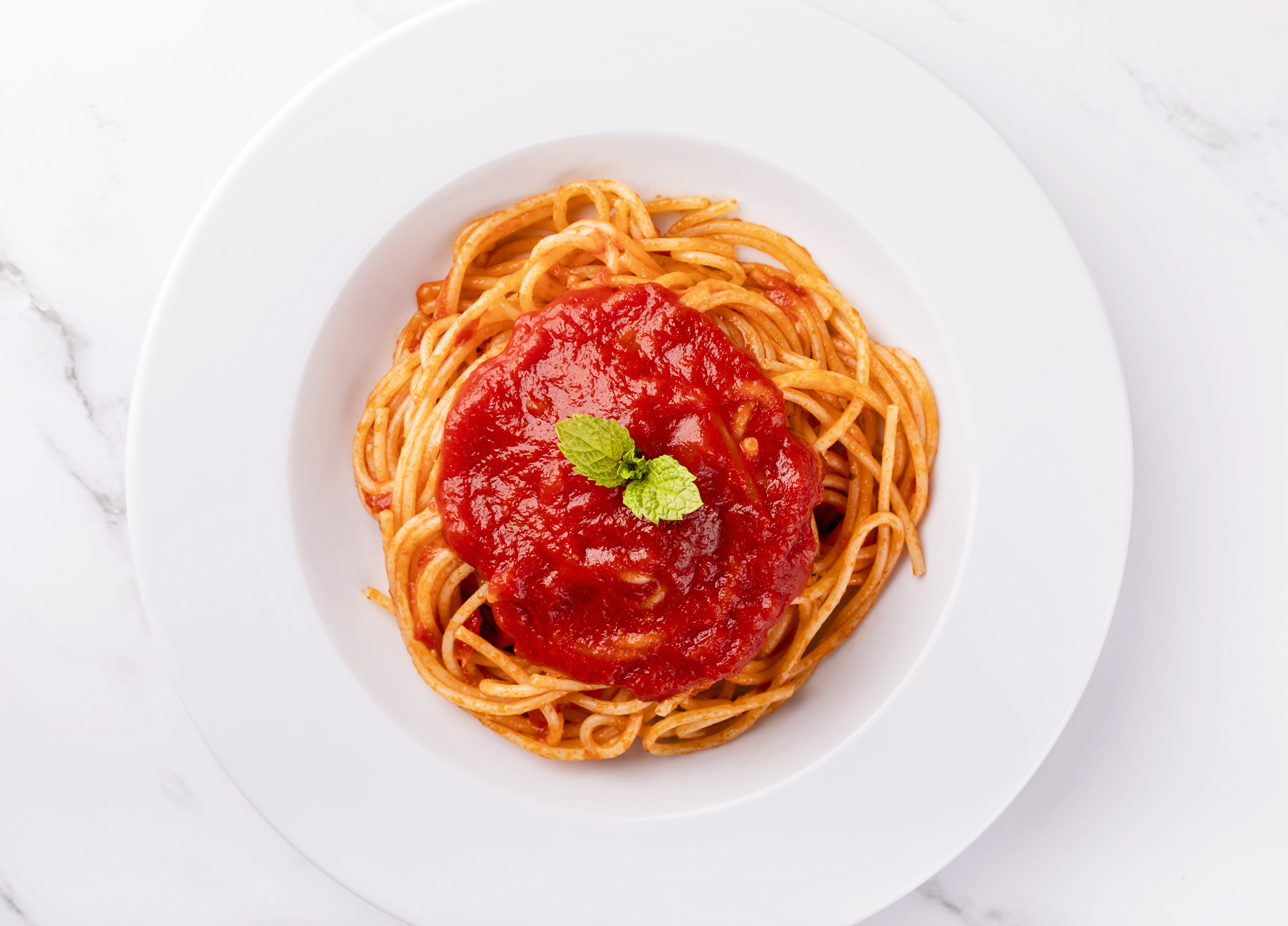 A bowl of spaghetti garnished with basil