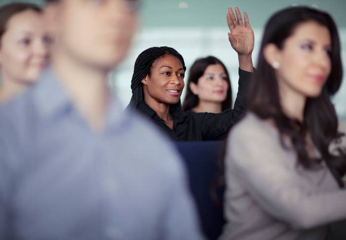 Black woman raising her hand in a meeting