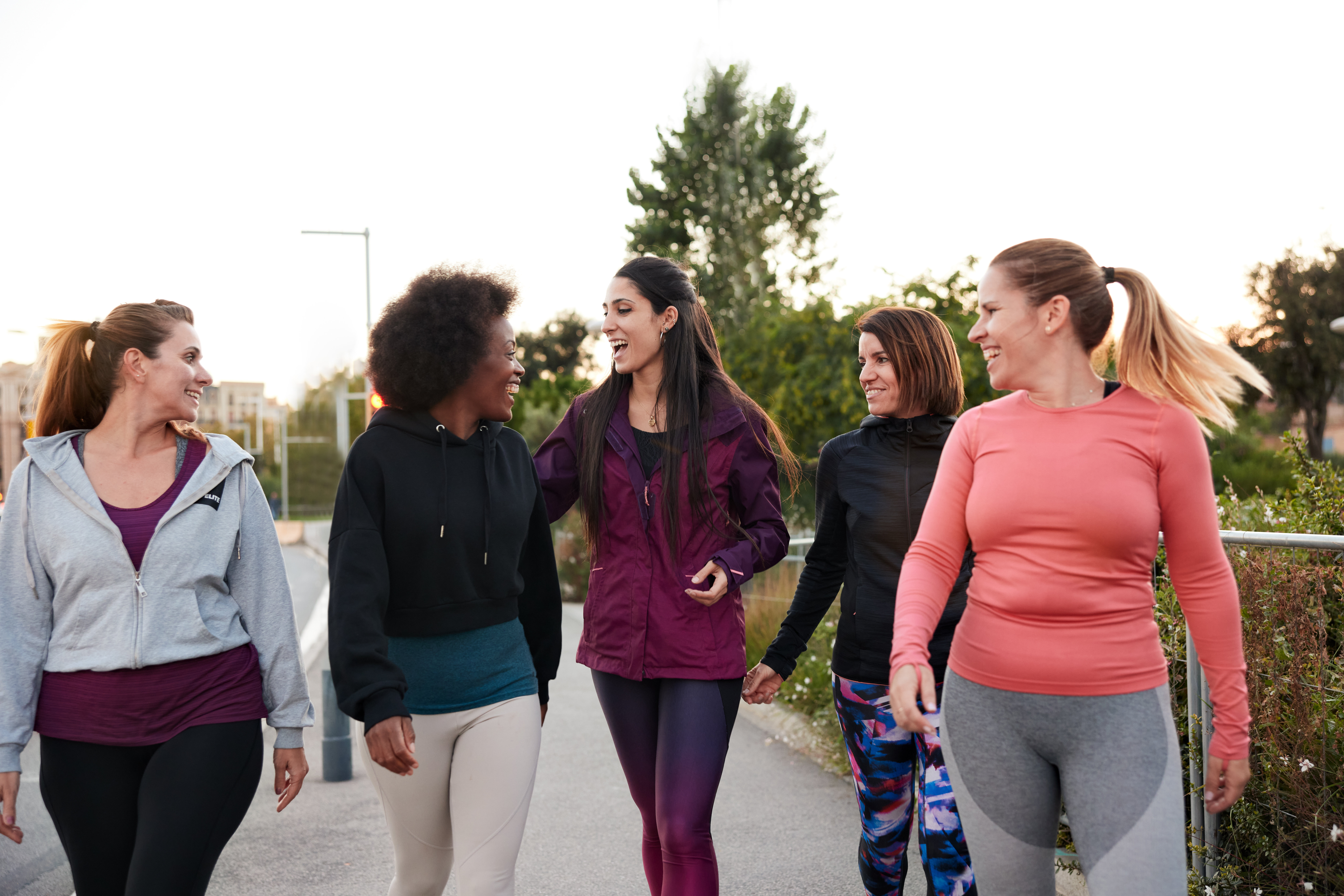 A group of women in athletic wear walking and talking together outdoors