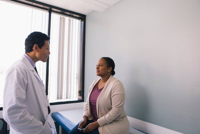 Doctor in white coat speaking with patient seated in medical office