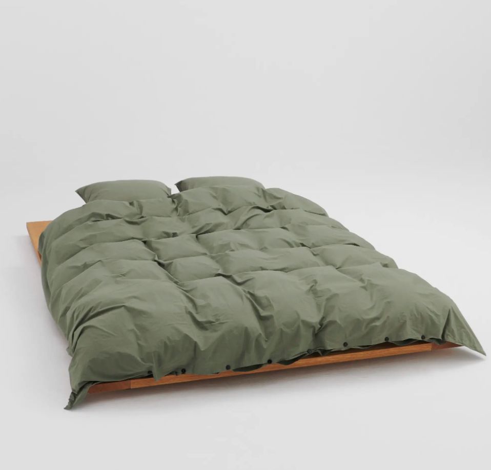 A green duvet on a wooden bed frame against a white background