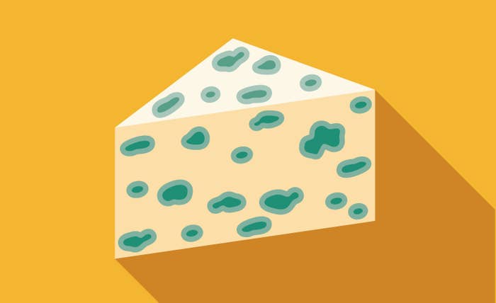 Illustration of a wedge of blue cheese with green mold spots on a yellow background