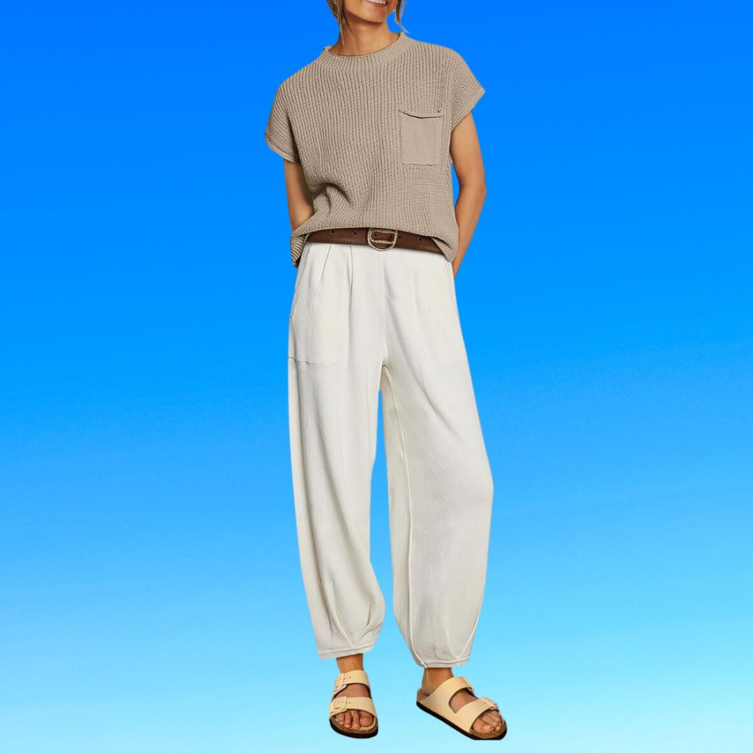 Person in a casual short-sleeved top, loose trousers with a belt, and open-toe sandals, standing with hands slightly behind them