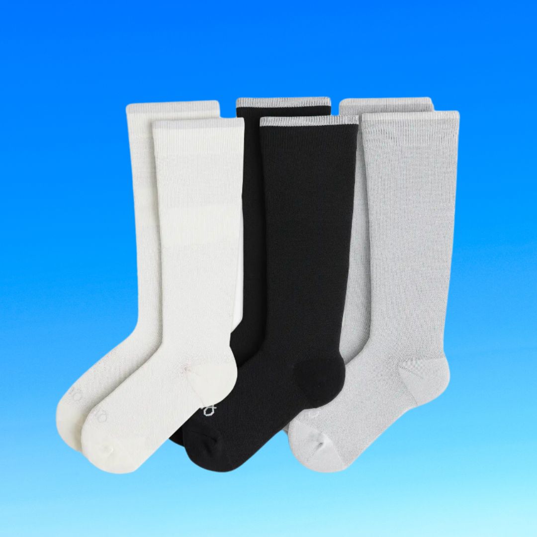 Three pairs of crew socks, one white, one black, one gray, displayed against a blue backdrop