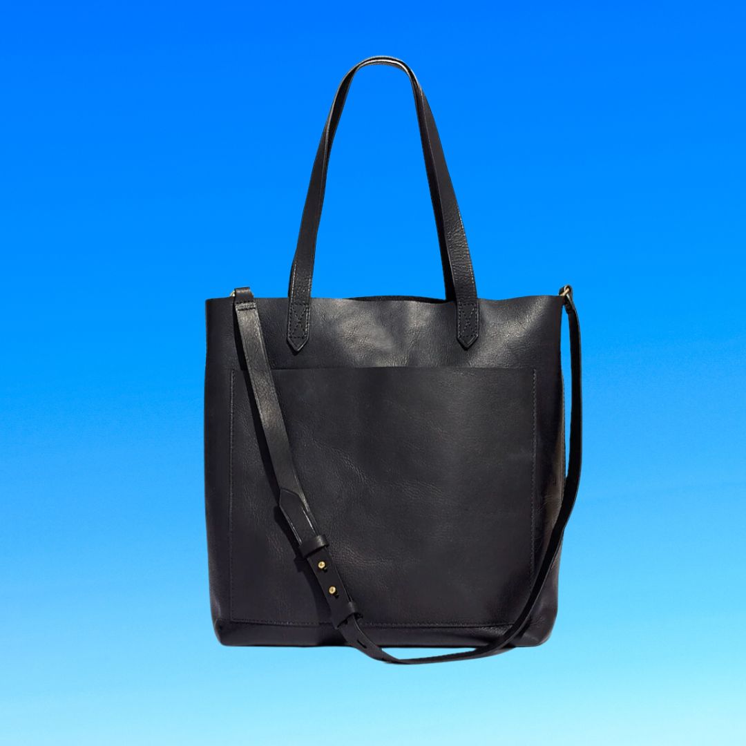 Black leather tote bag with shoulder strap against a blue background