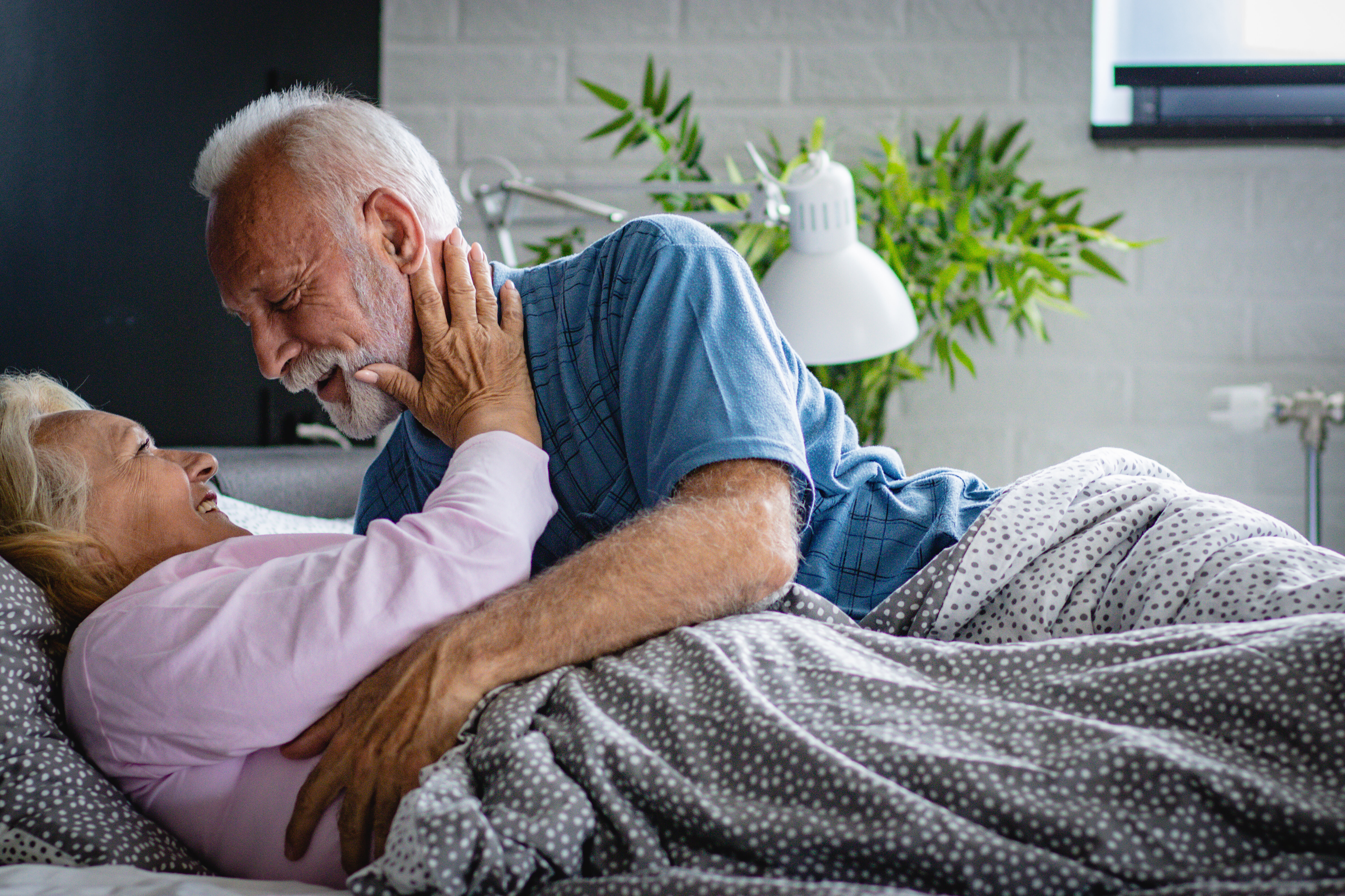Elderly couple sharing an affectionate moment in bed, smiling and embracing