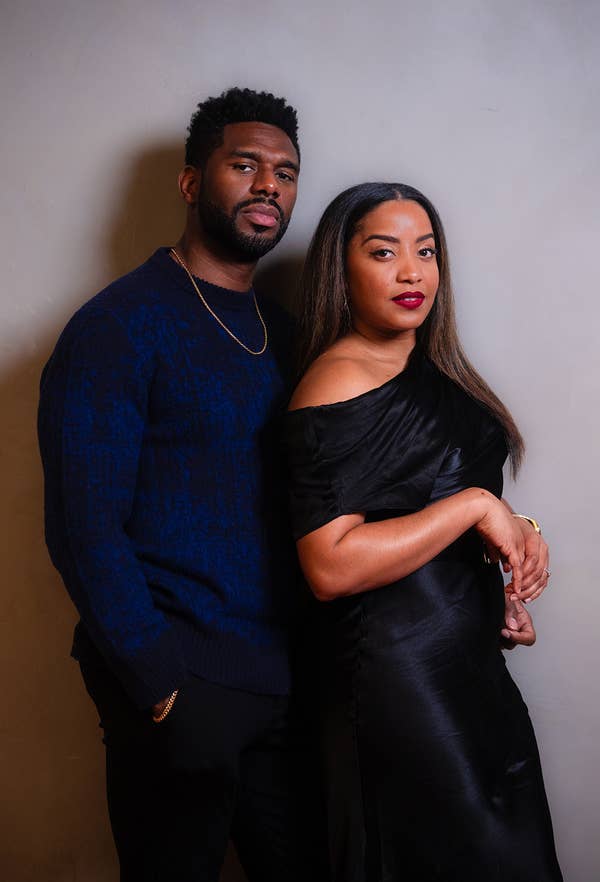 A couple posing closely together, man in a sweater and woman in a black dress