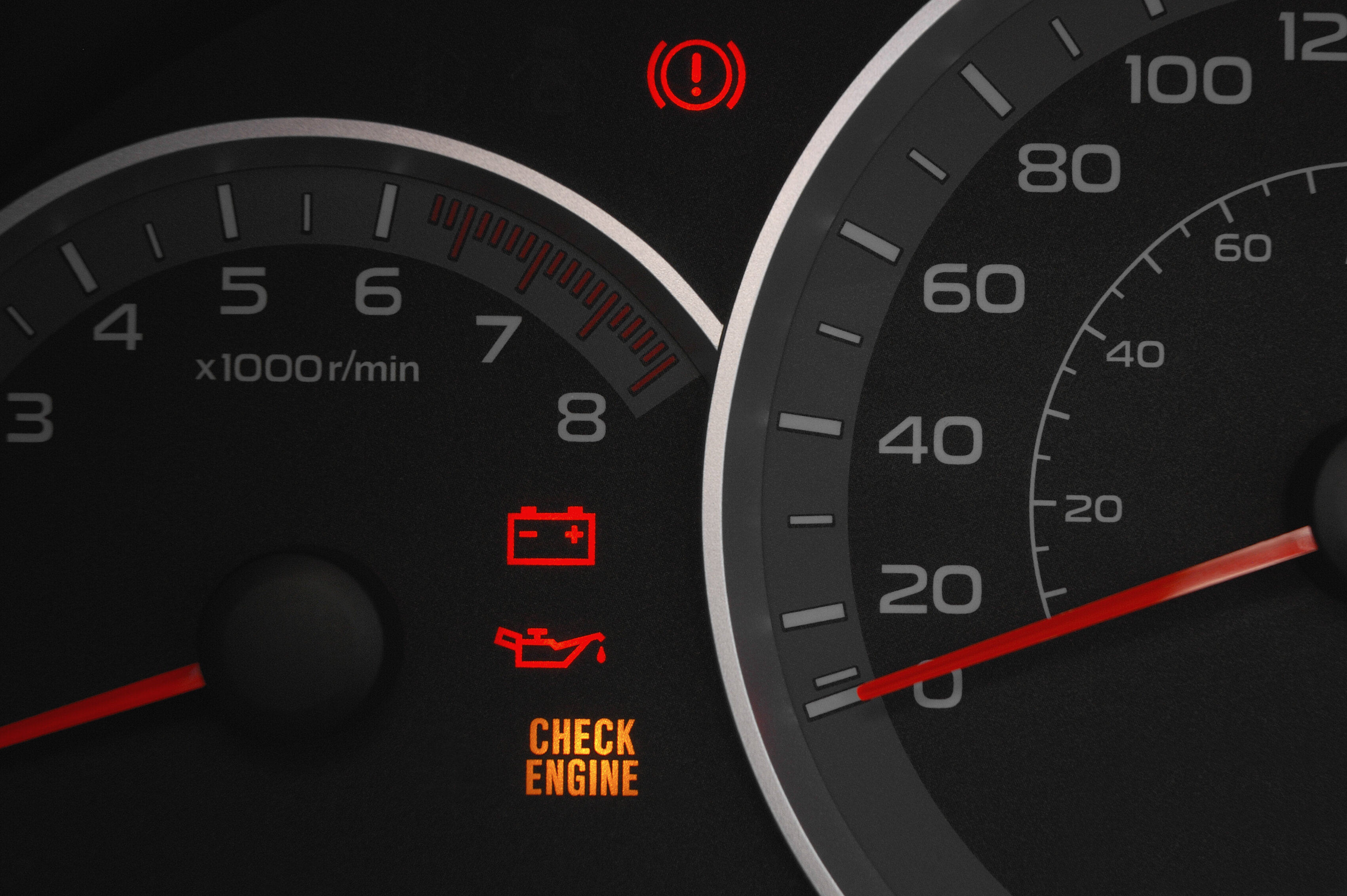 Car dashboard showing illuminated check engine light and battery warning light