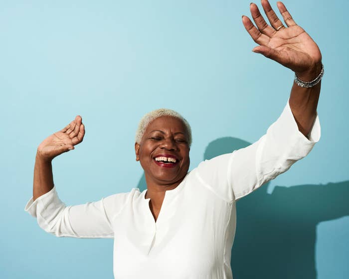 A smiling, happy aging woman with her arms raised in the air