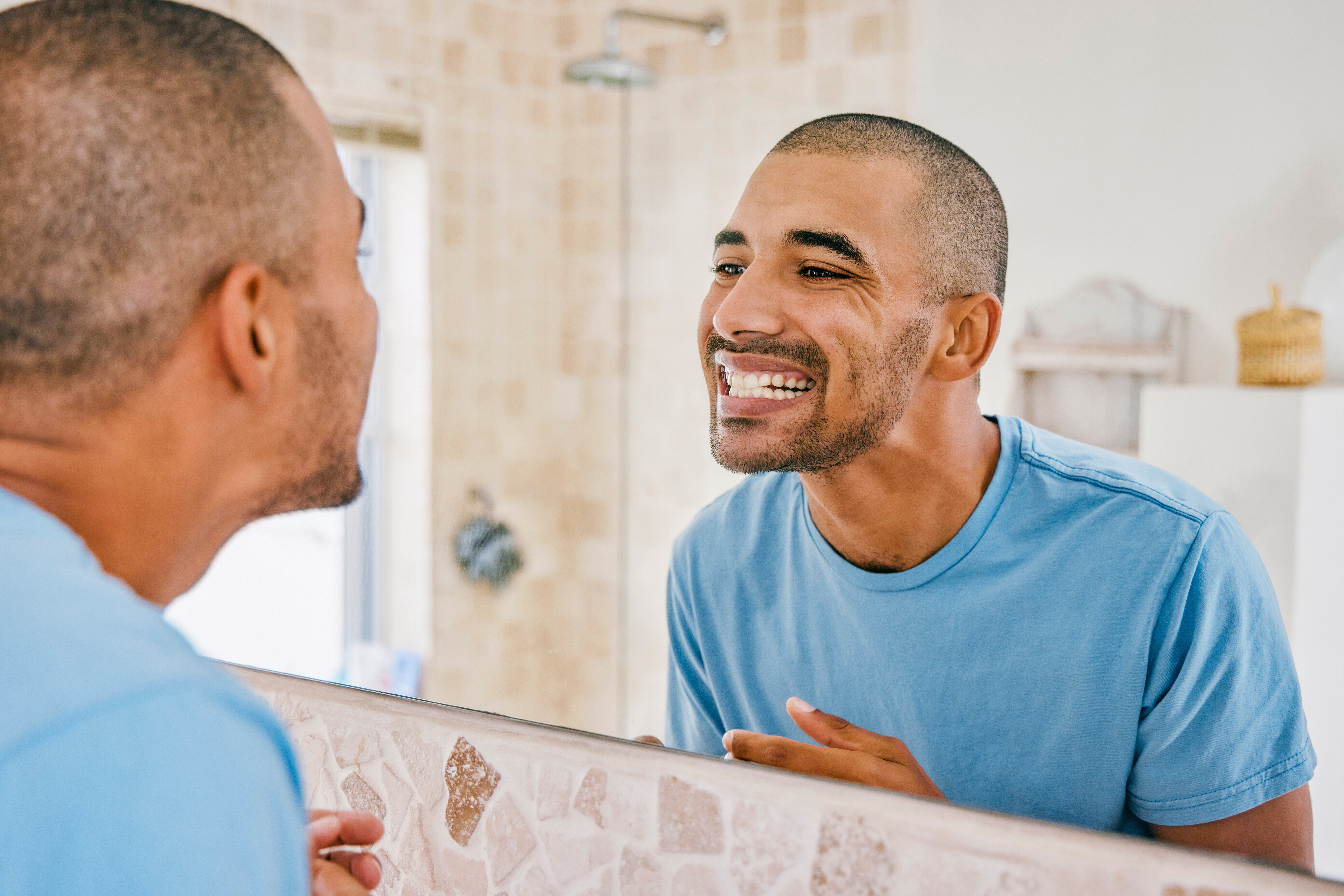Man smiling at his reflection, practicing self-care for a Goodful lifestyle piece