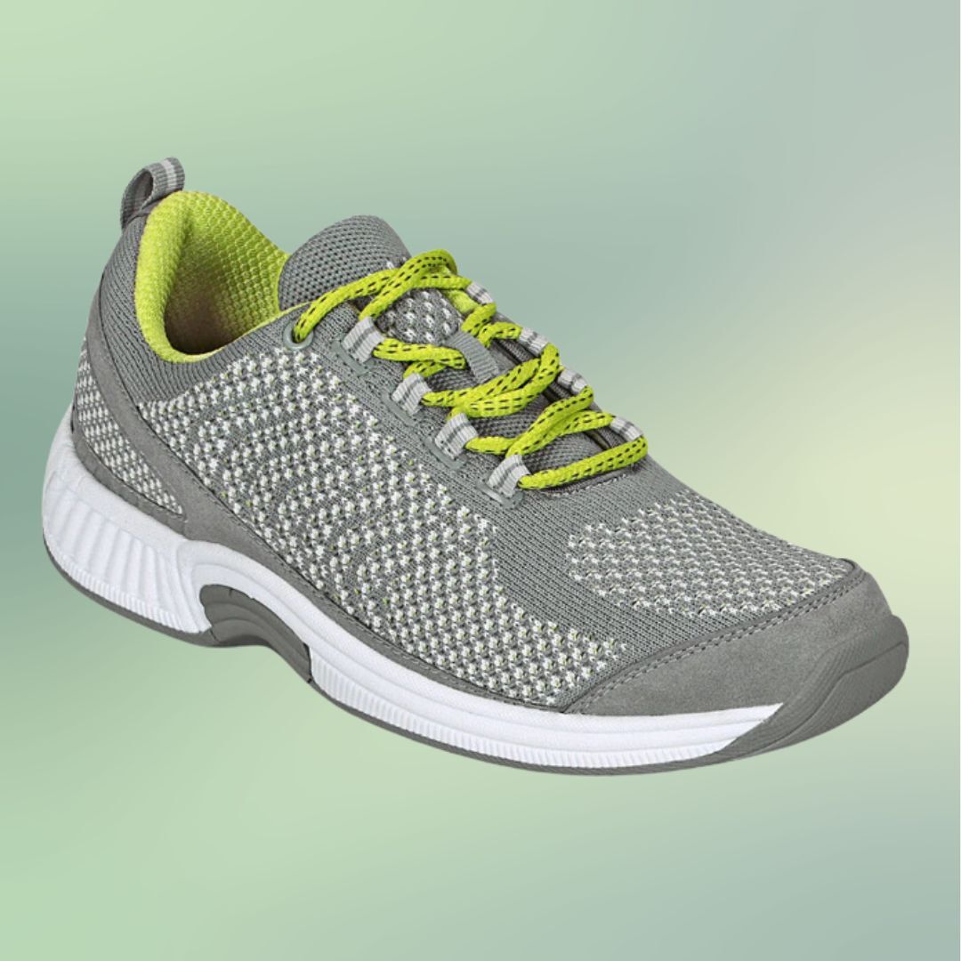 Gray athletic shoe with yellow laces on a greenish background