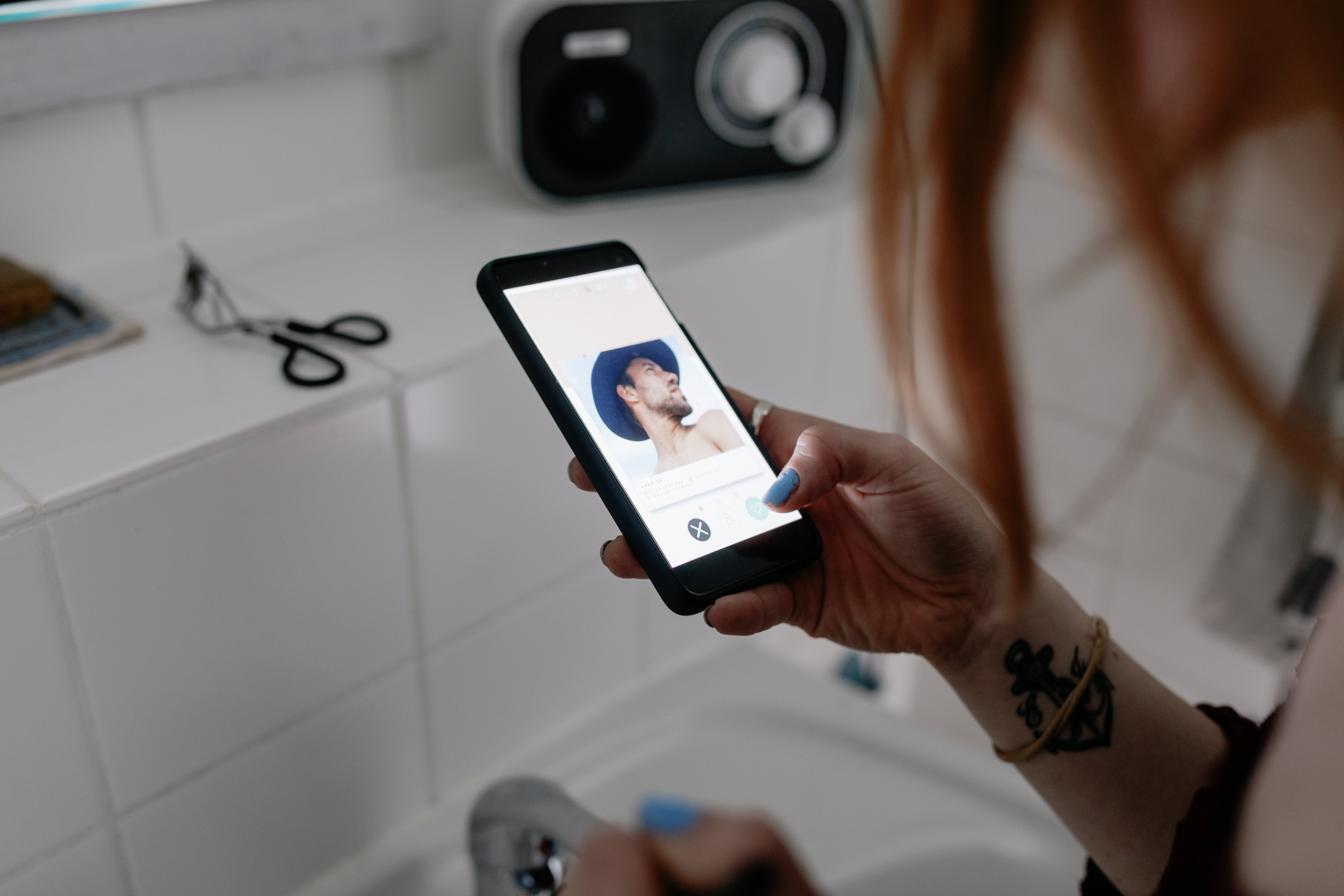 Person holding smartphone with a photo of a person displayed on screen, in a bathroom setting