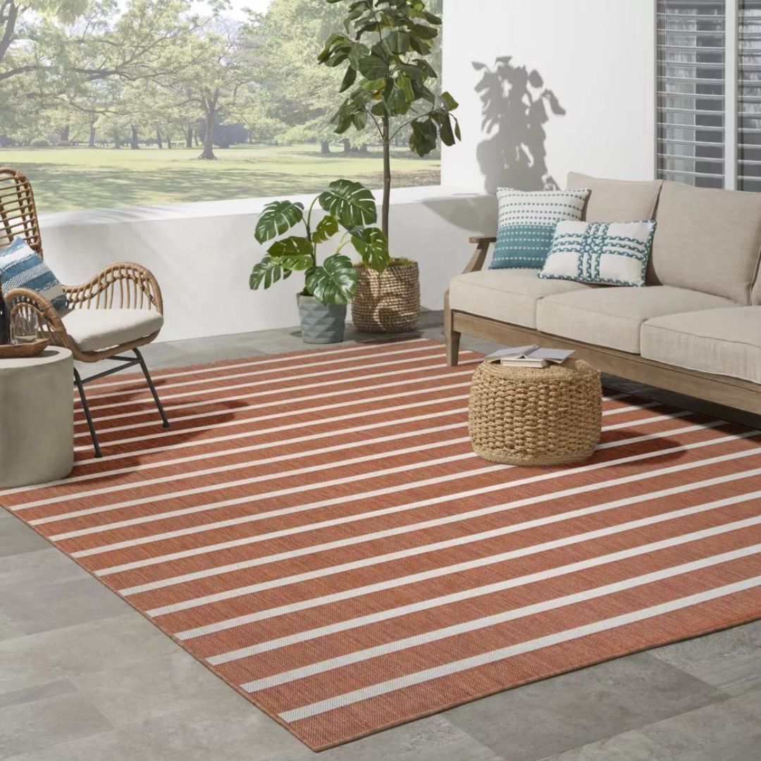 An orange and cream striped outdoor rug on a porch with patio furniture
