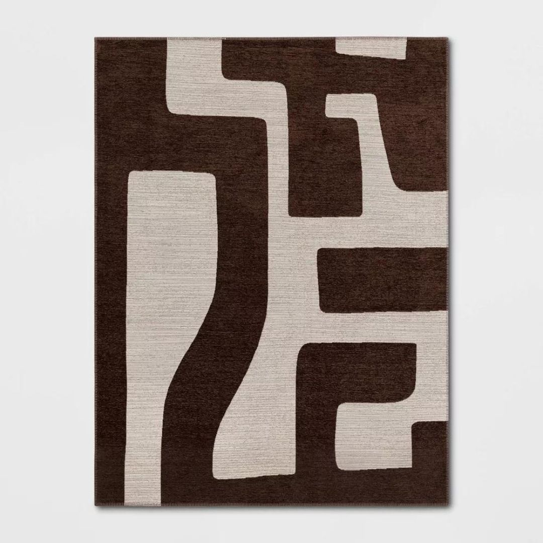 A dark brown and cream rug with a large, abstract pattern on it