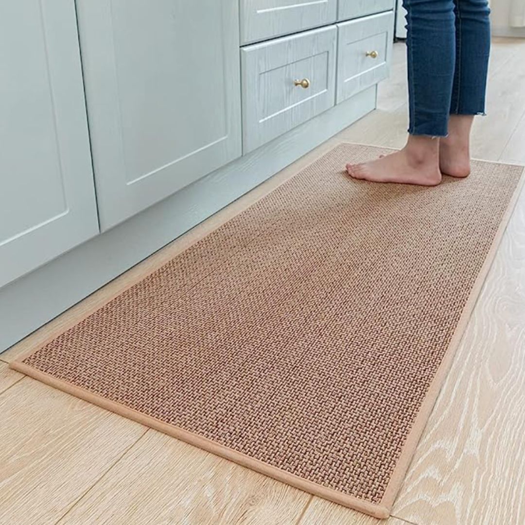 A person in a kitchen standing on a textured, neutral-colored rug on a wood floor