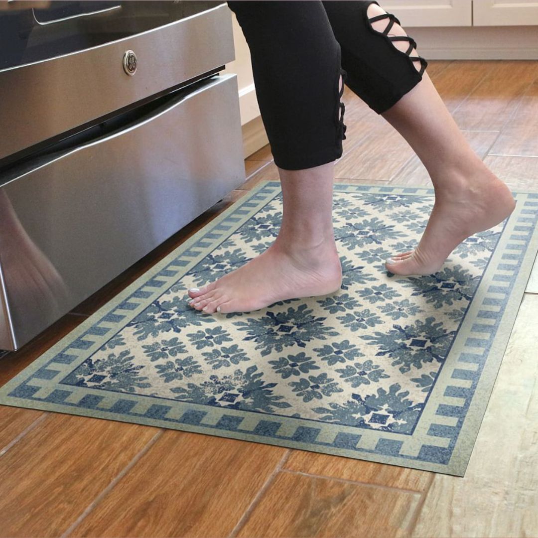 A person standing on a blue patterned floor mat on a wooden floor