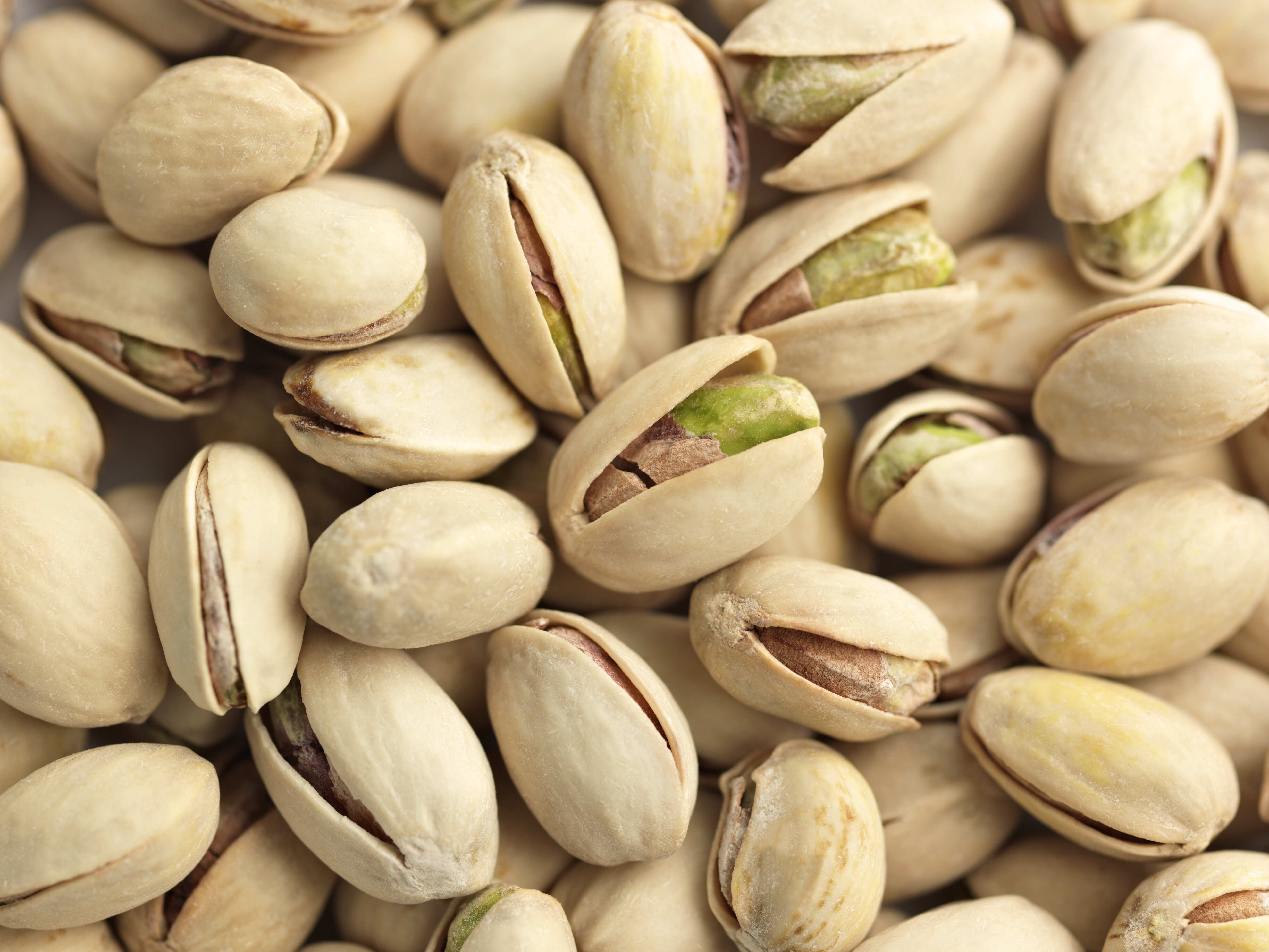 Close-up of several whole pistachios with shells partially opened