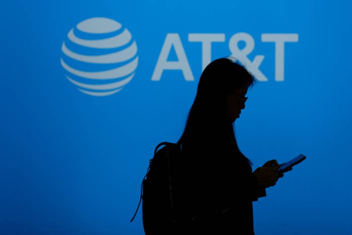 Silhouetted person using a smartphone with the AT&amp;T logo in the background