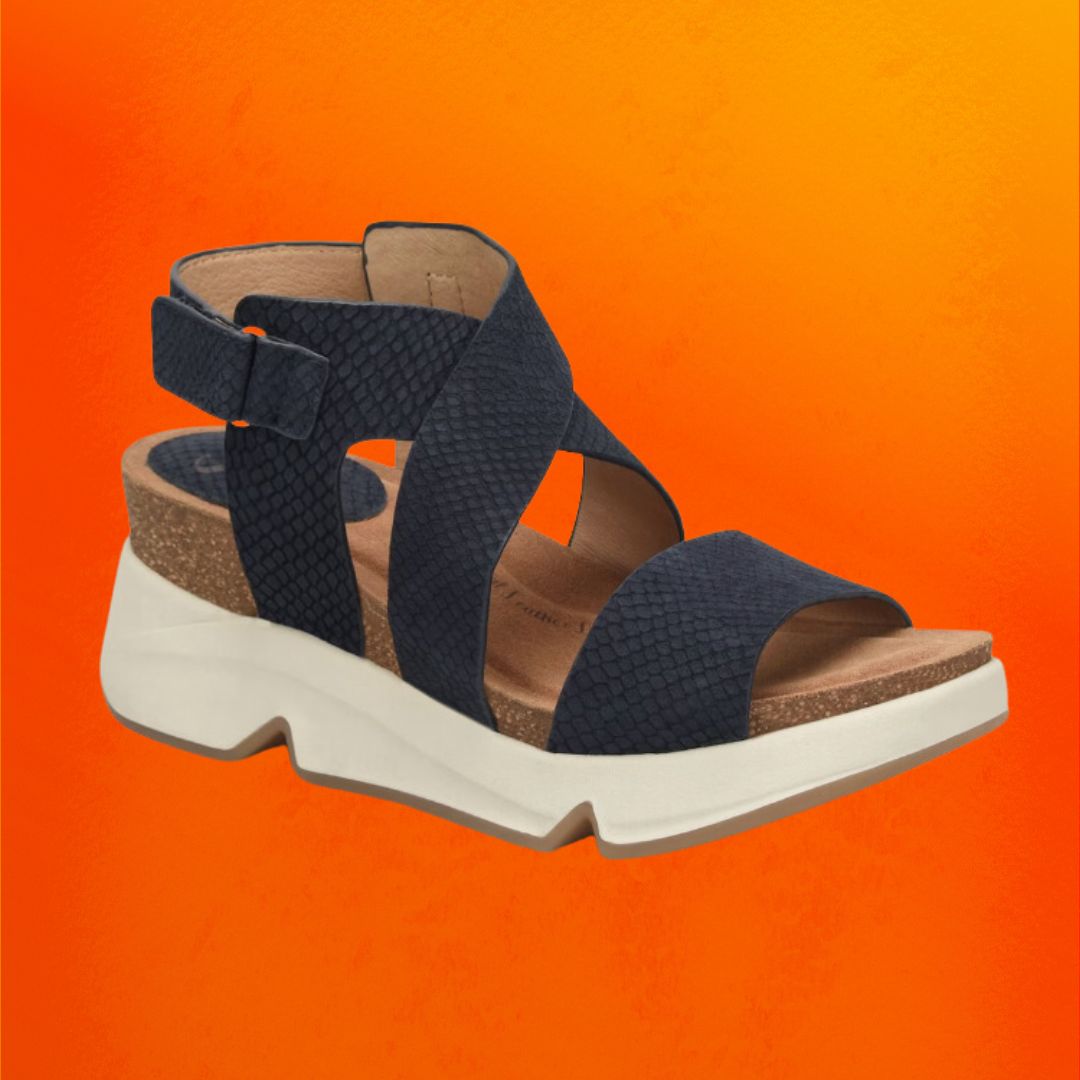 Navy wedge sandals with wide, crossing straps against an orange background