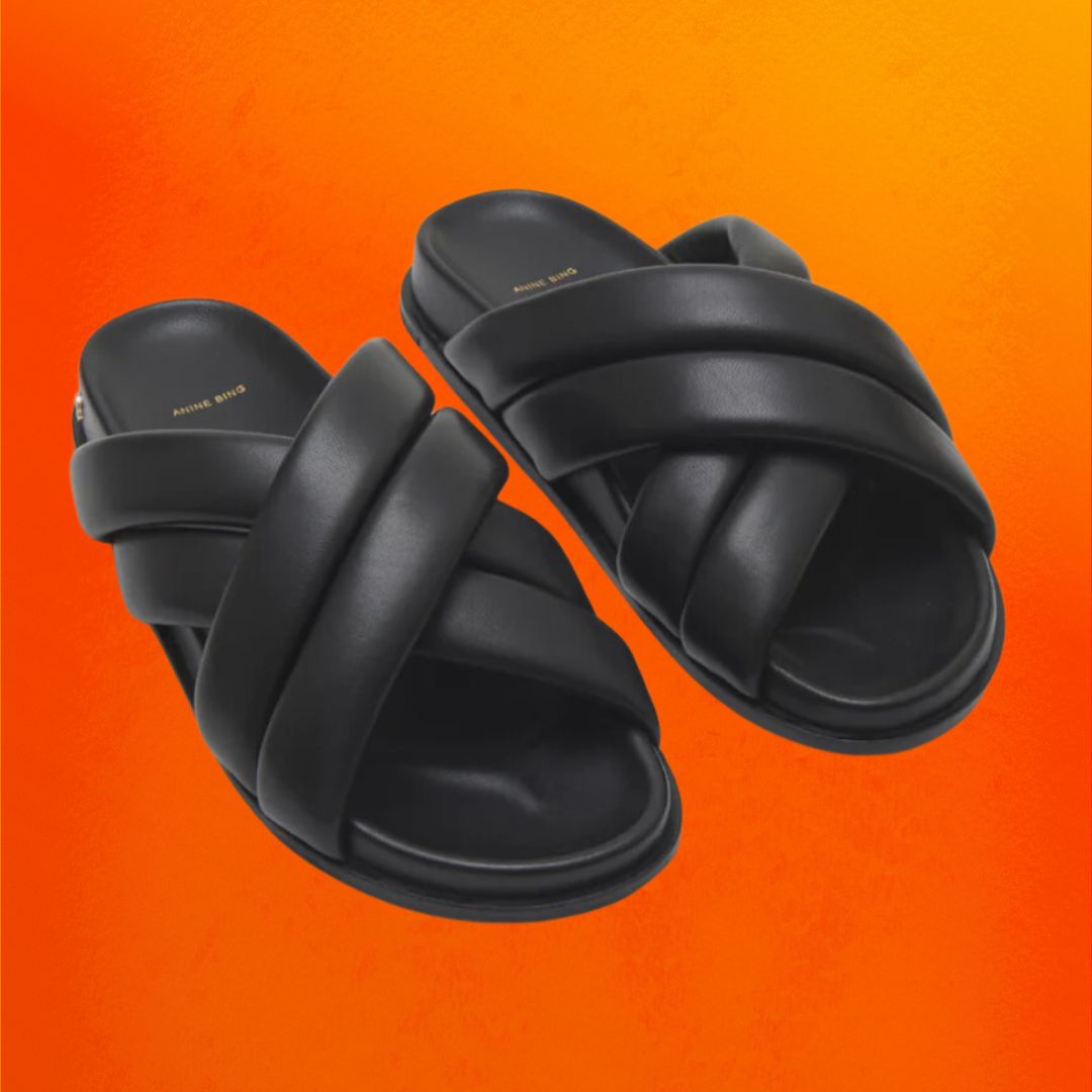 Black slide sandals against an orange background