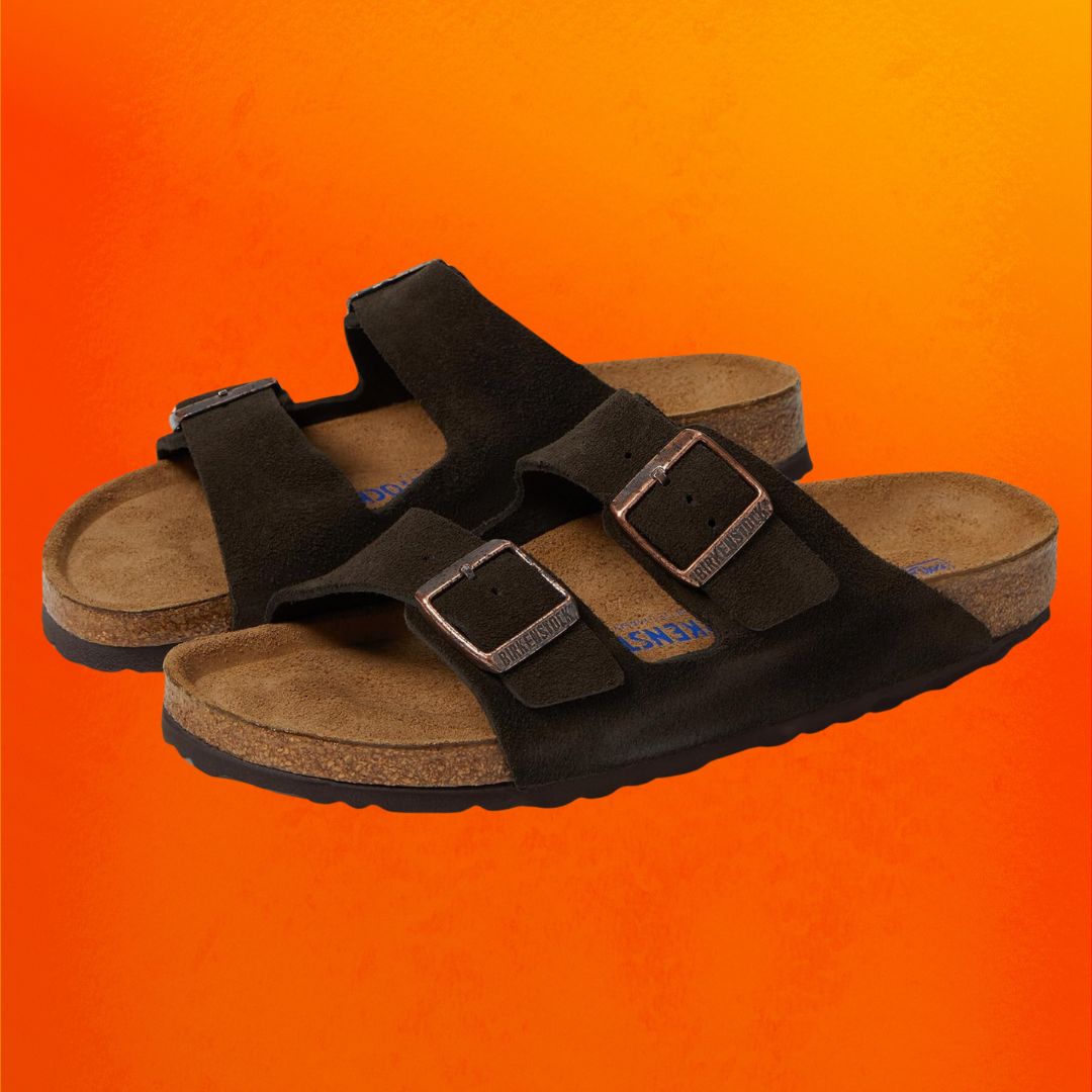 Black Birkenstock slide sandals against an orange background