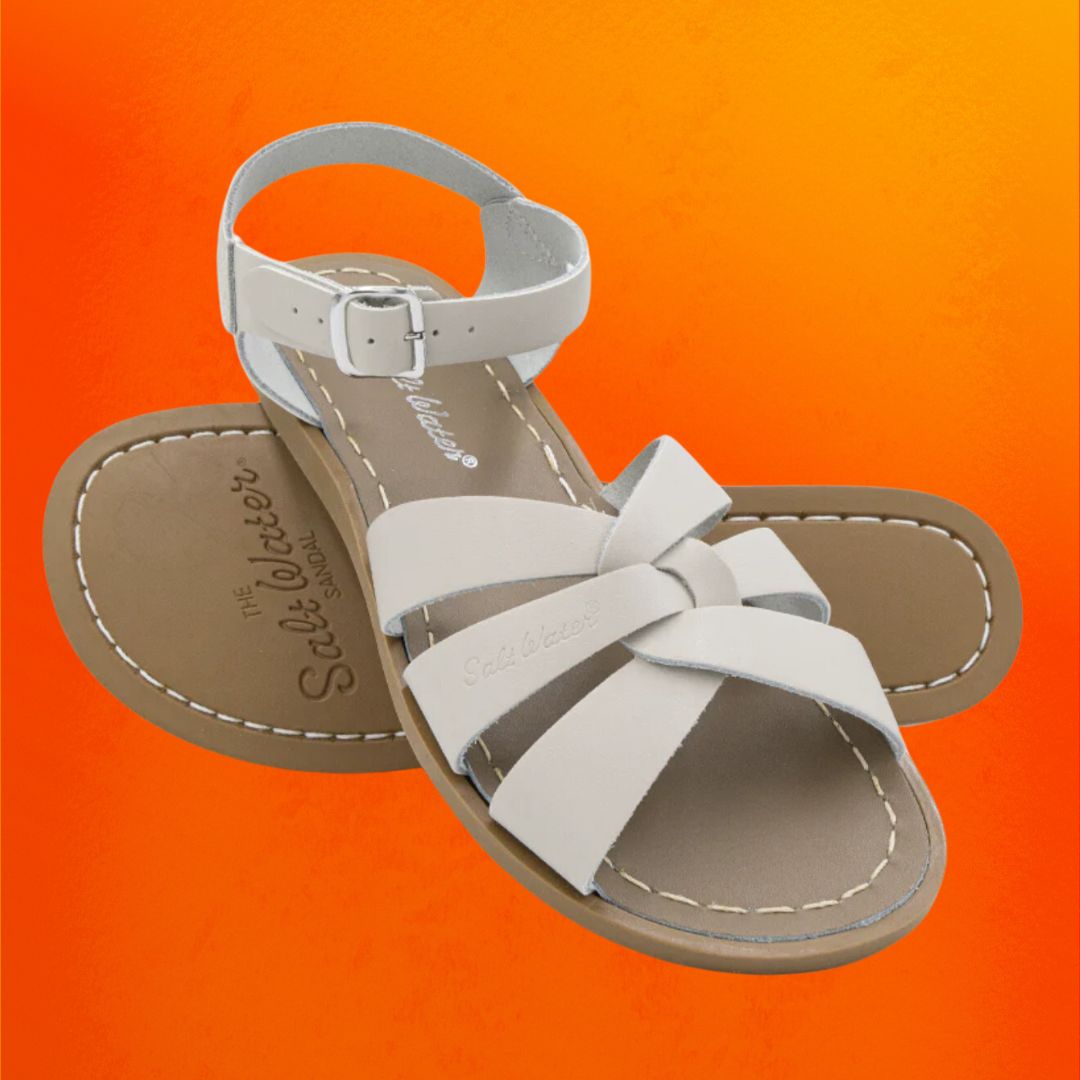 The Salt Water Original sandals in the color white against an orange background