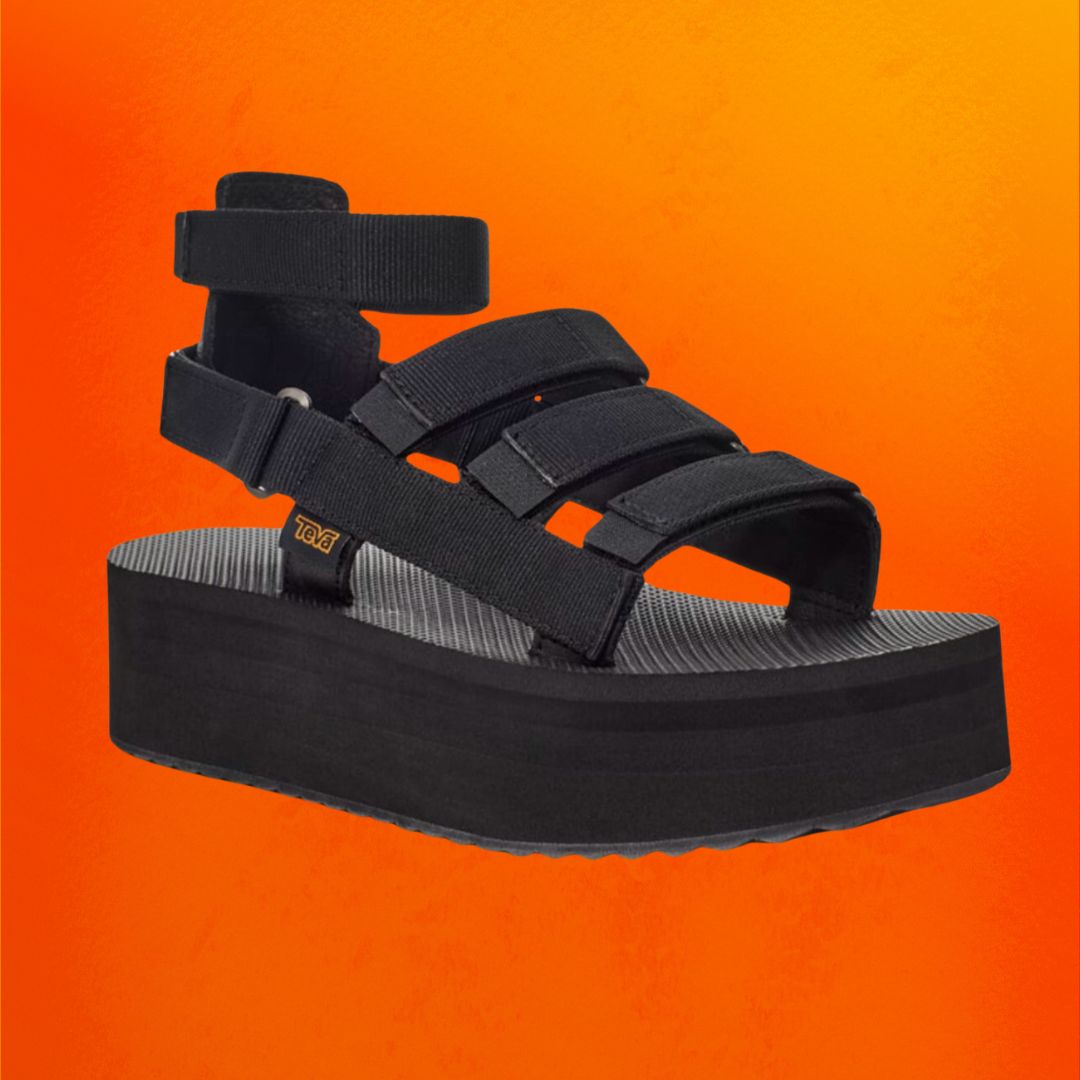 Black platform Teva sandals against an orange background.