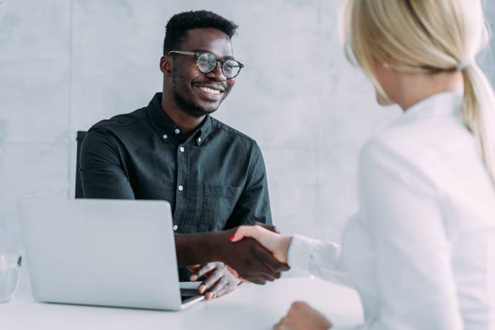 Two professionals shaking hands over a desk, signaling a successful job interview or business agreement