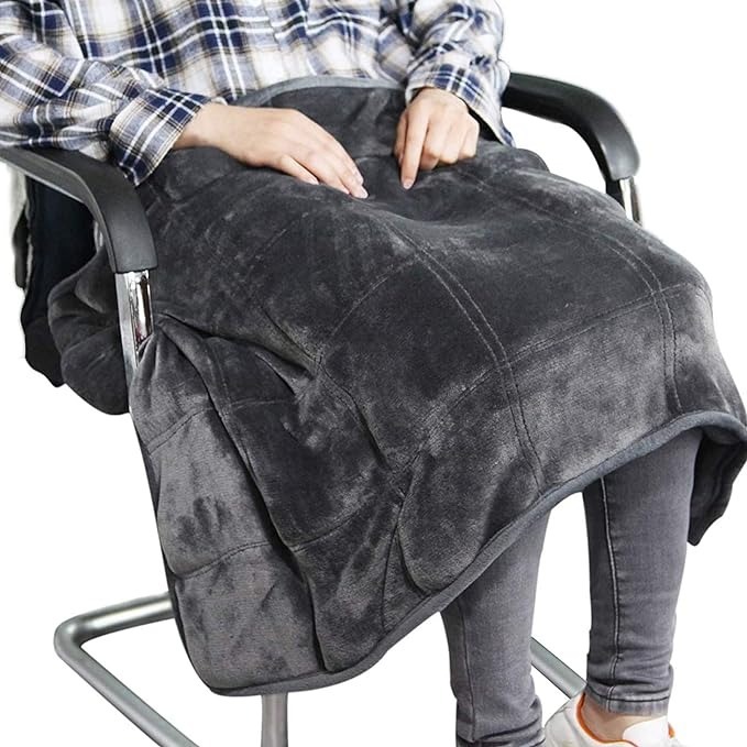 A person sitting in a chair with a dark grey weighted blanket on their lap