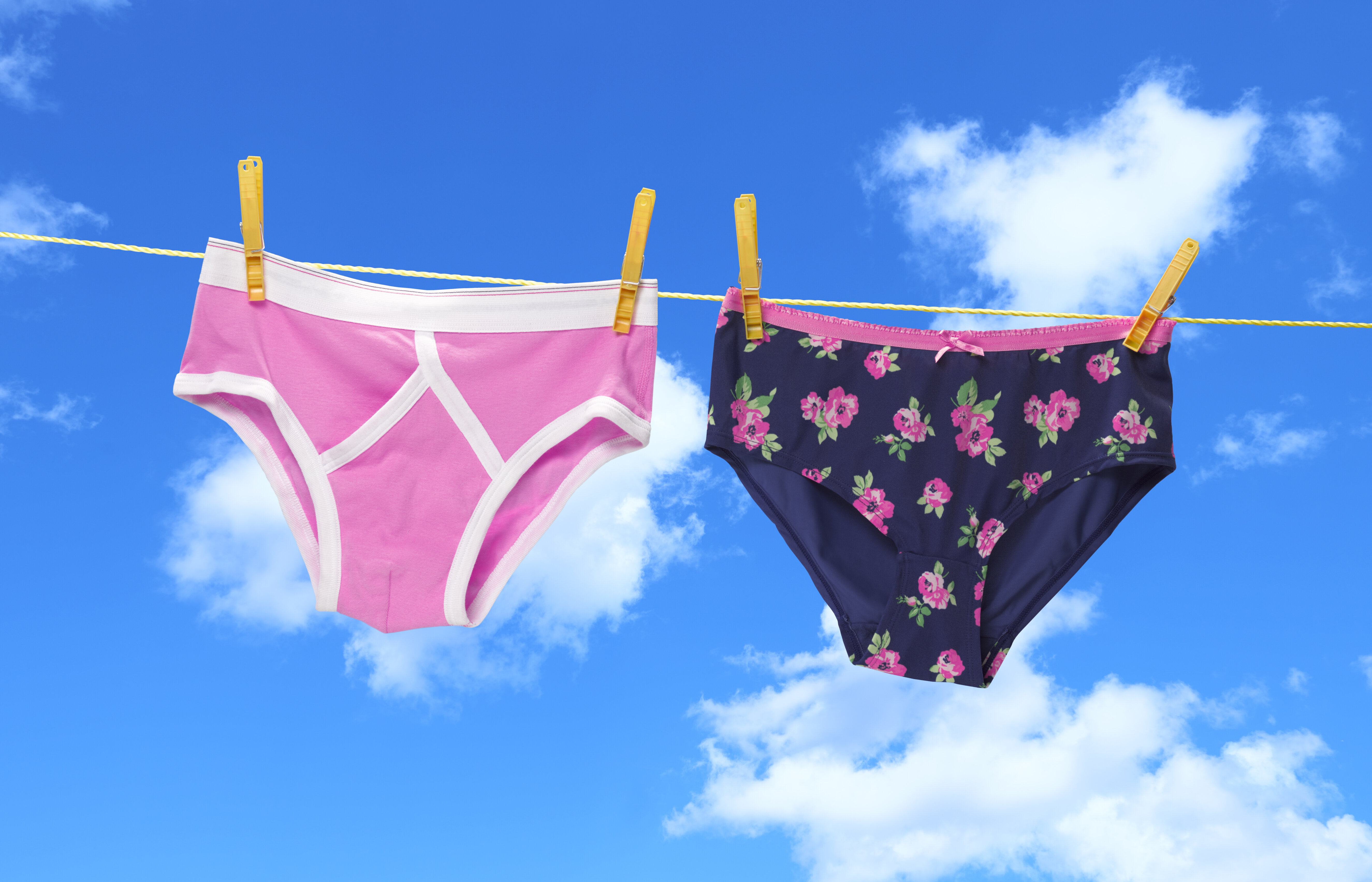 Two pairs of underwear hanging on a clothesline against a blue sky