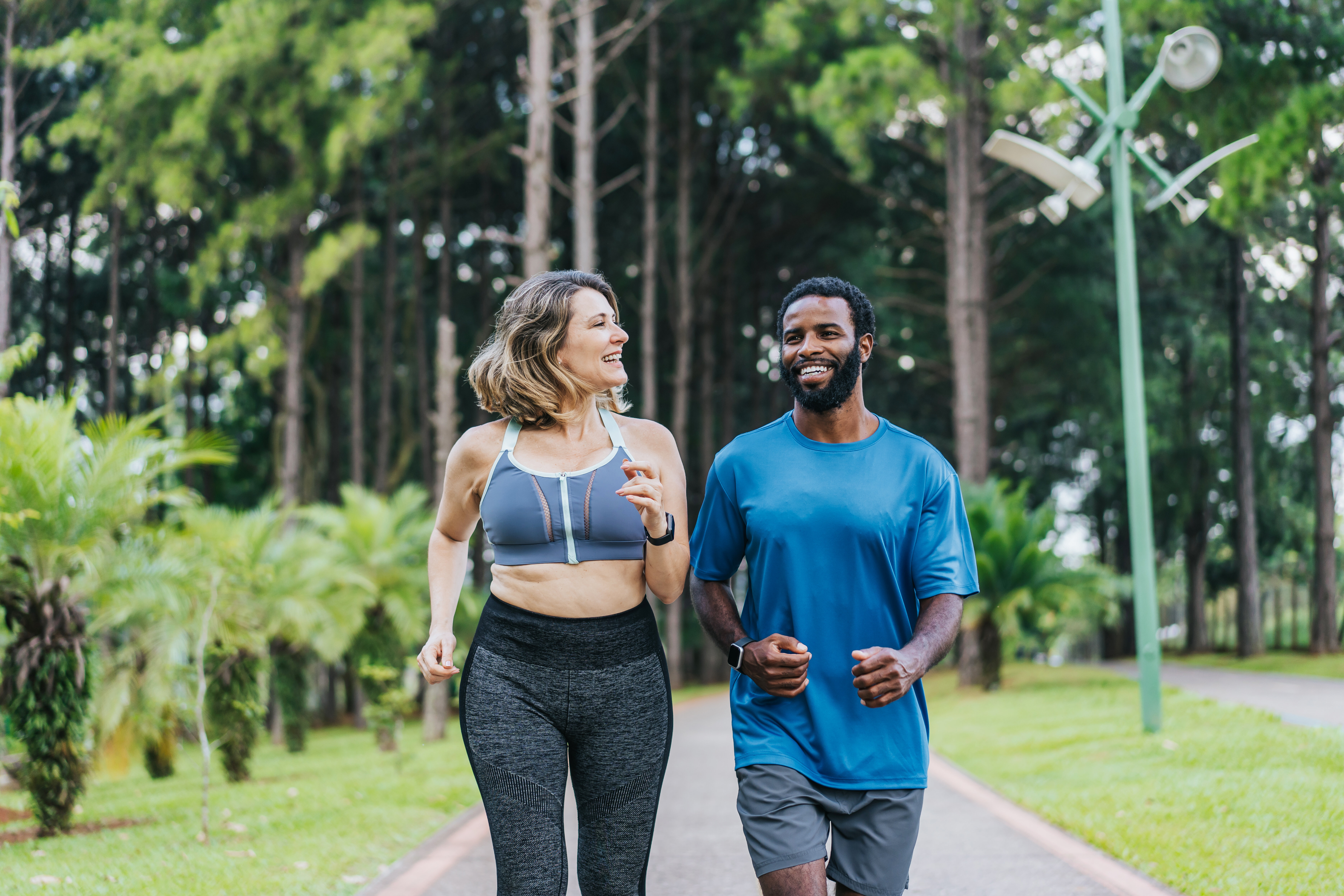Two people jogging together in a park, smiling and conversing