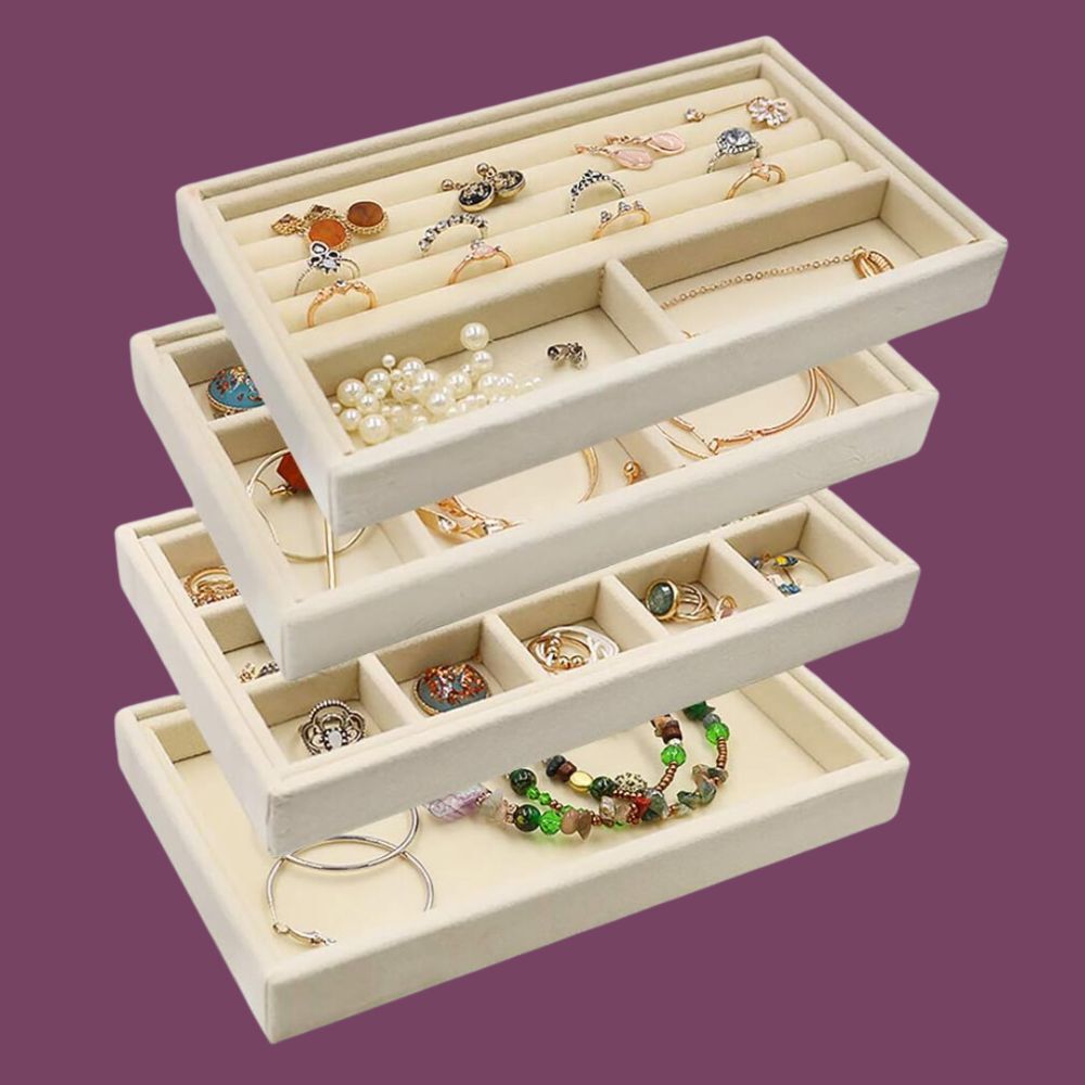 A set of four, white, stackable, velvet-lined trays for organizing jewelry