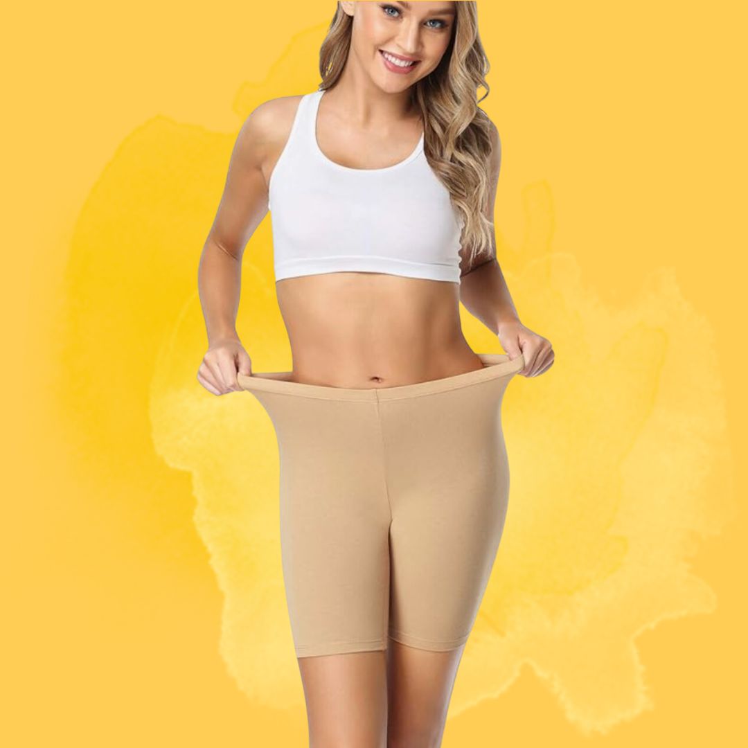 Person successful a achromatic sports apical and beige shapewear shorts, smiling and demonstrating stretchiness against a neutral background