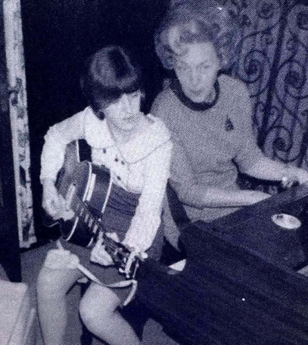 The author's mother playing guitar likely at home or in an informal setting