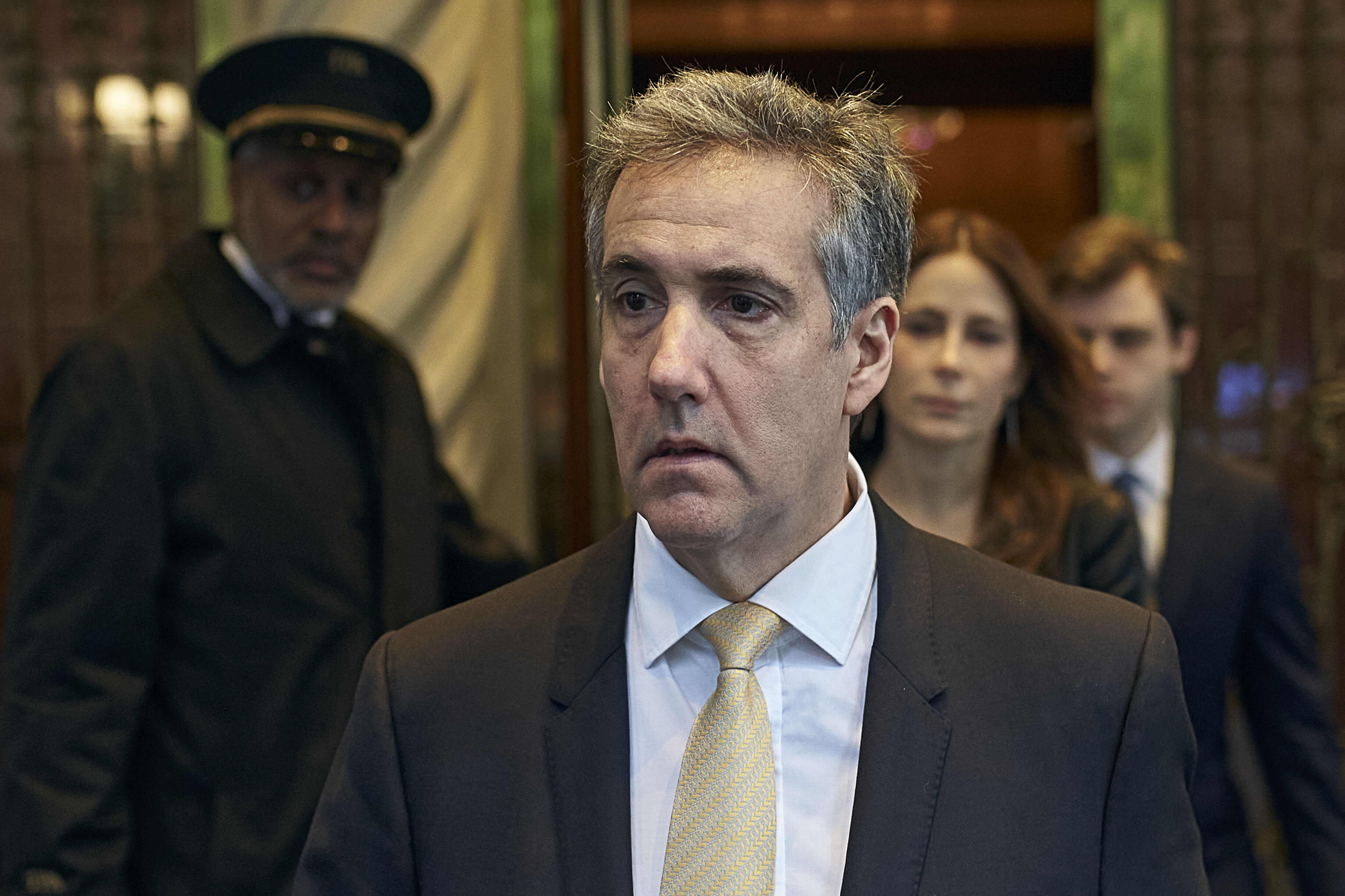 Michael Cohen enters a building, followed closely by a man in uniform, a woman, and another man